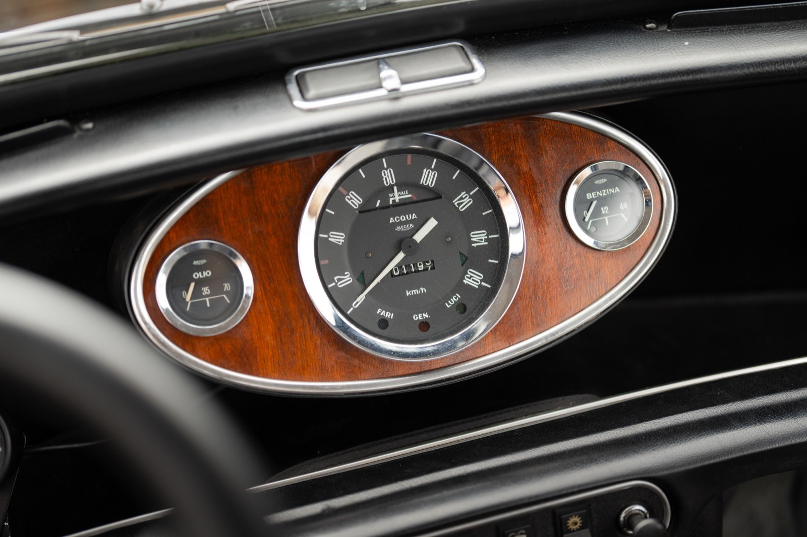 Close-up of a luxury car's dashboard featuring a round clock with a wooden trim.