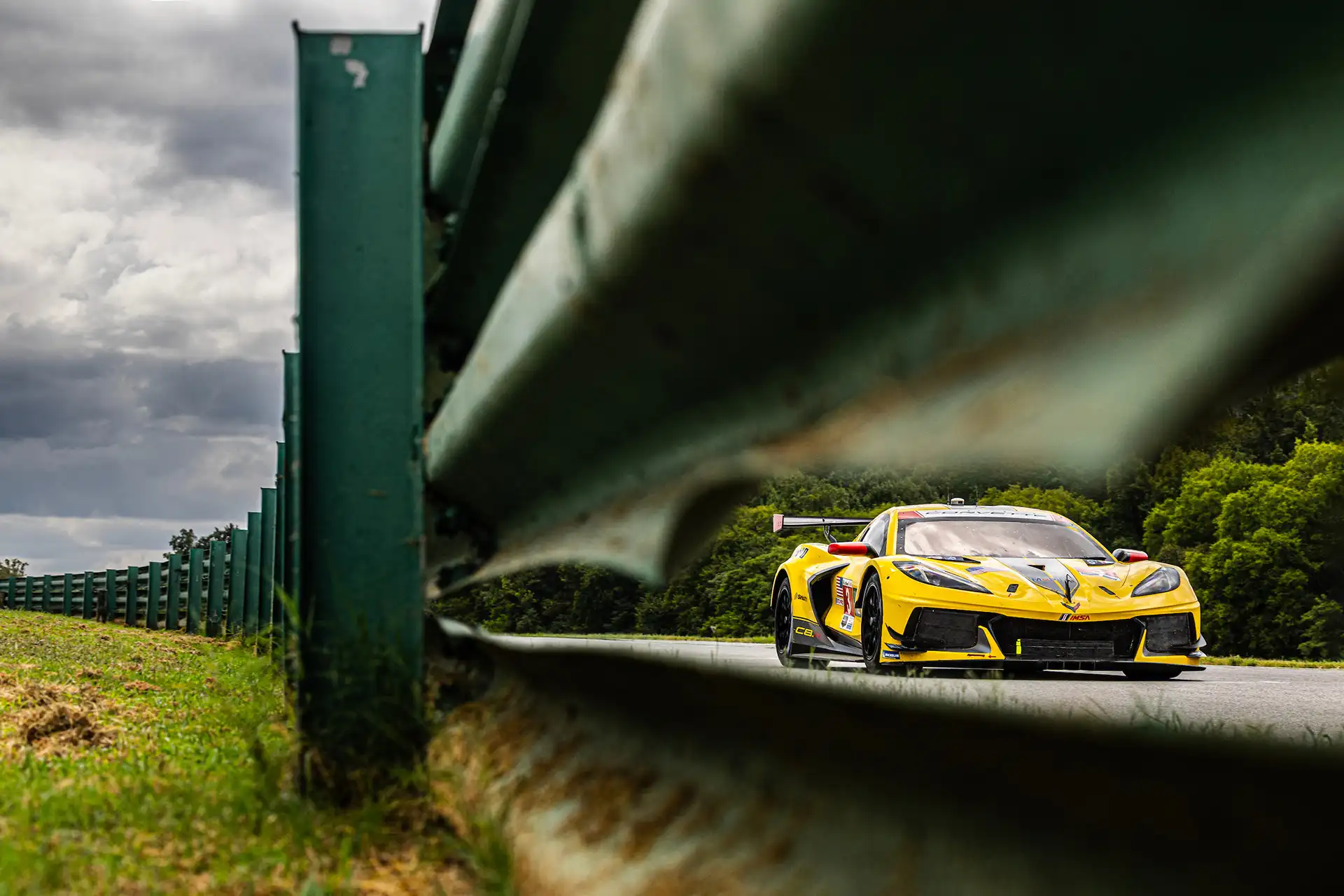 A yellow sports car by guard rails.