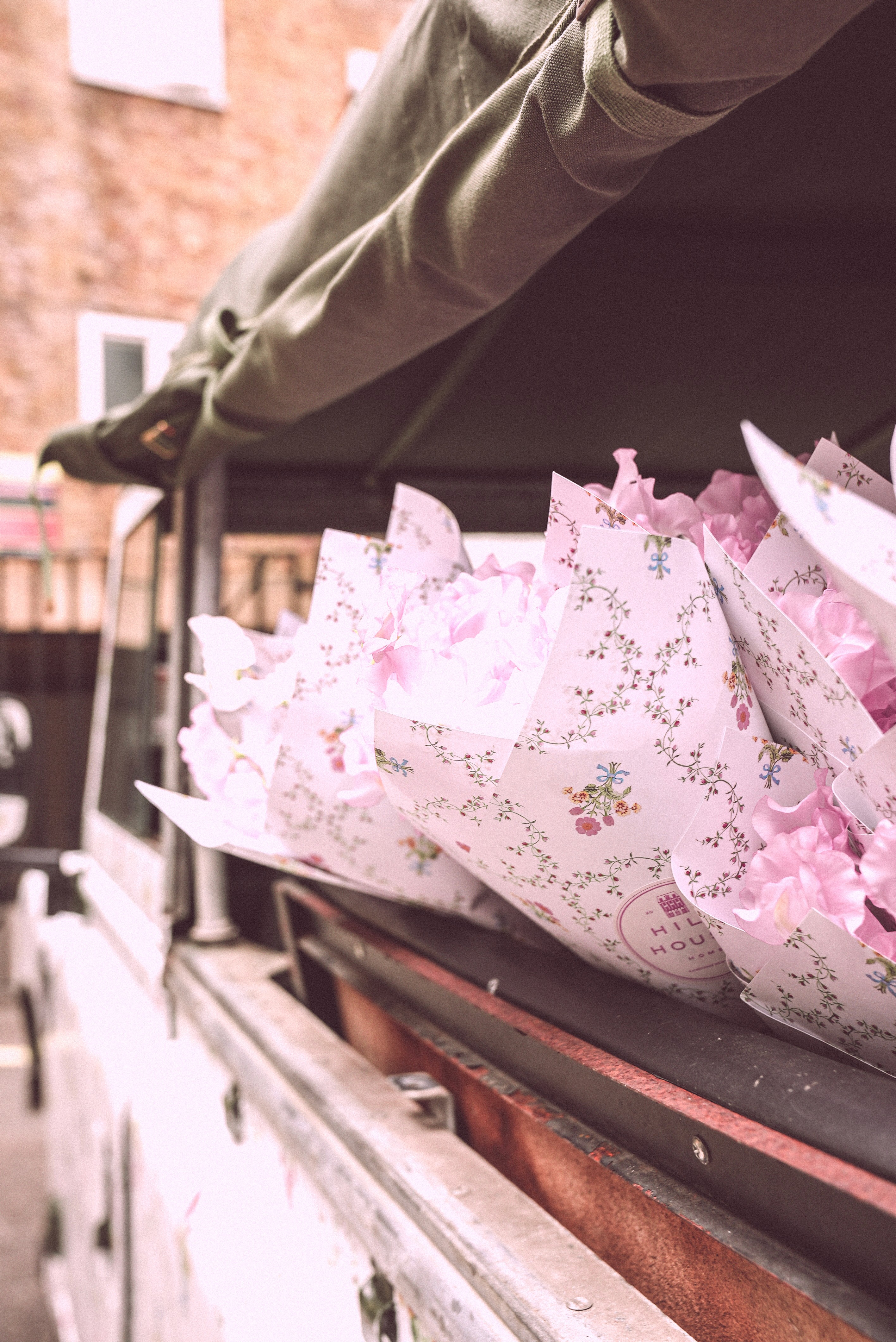 Bride sitting on ground against wall, groom standing nearby