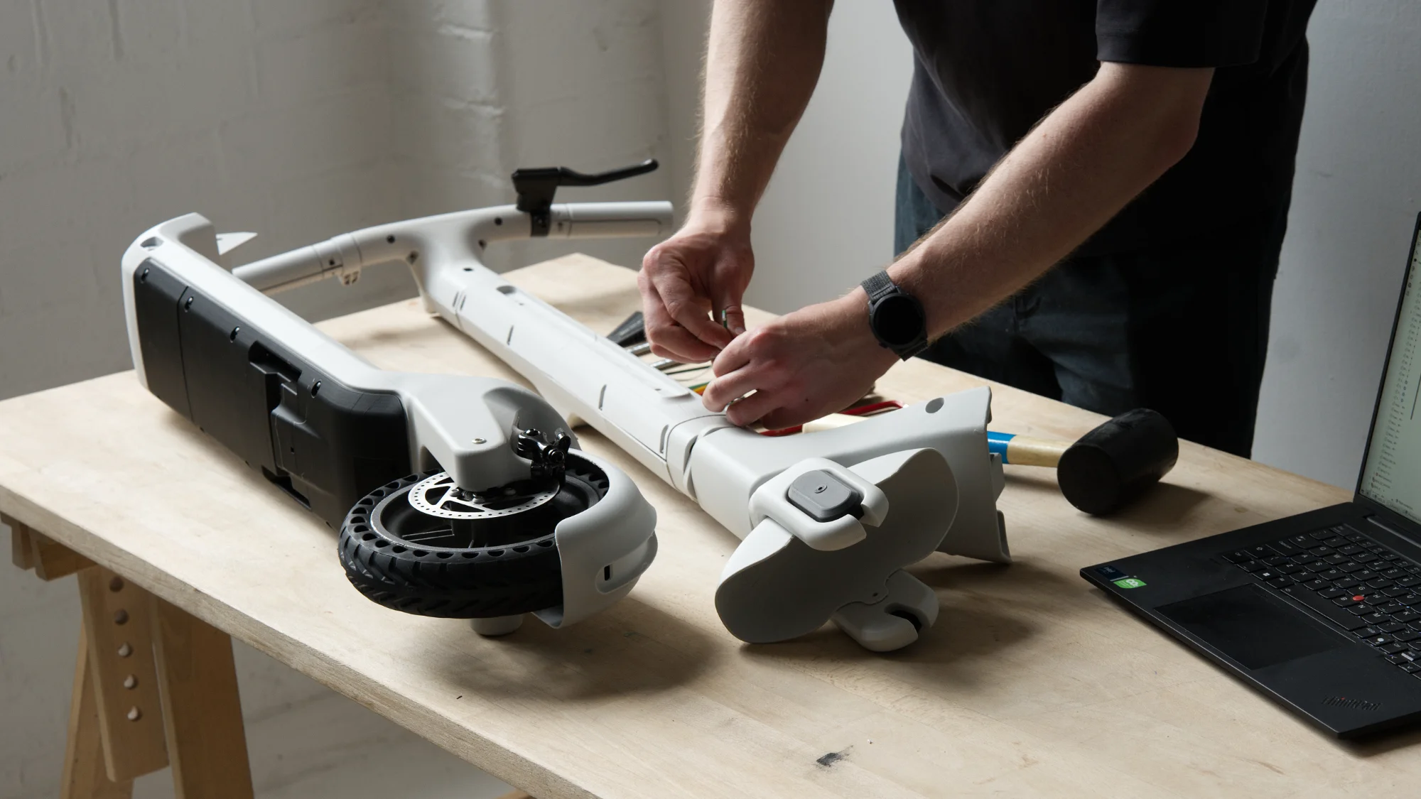 Industrial designer assembling a 3D printed electric scooter prototype during product development and testing.