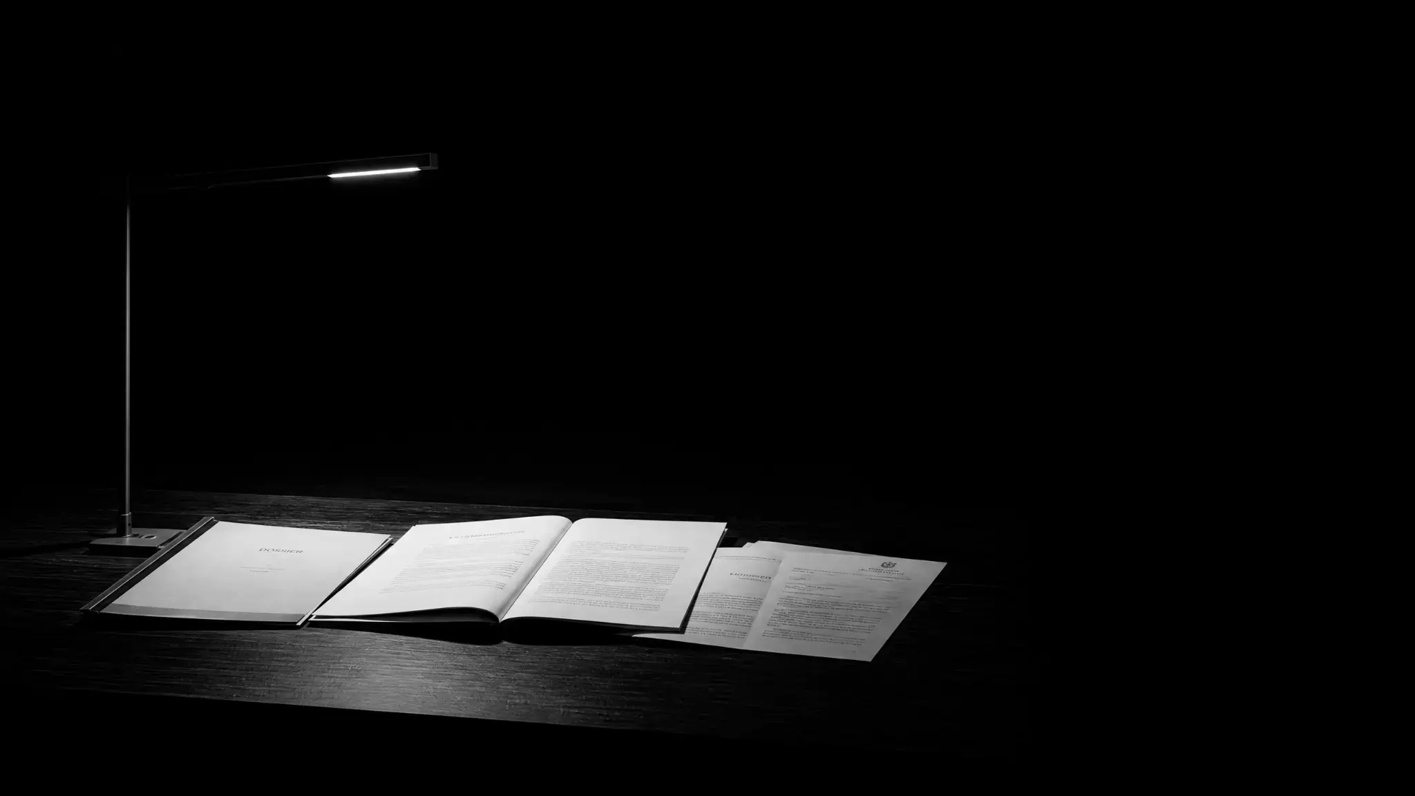 Lampe de bureau éclairant un dossier dans l'obscurité, symbole de la prévention des difficultés et de la gestion de crise en entreprise.