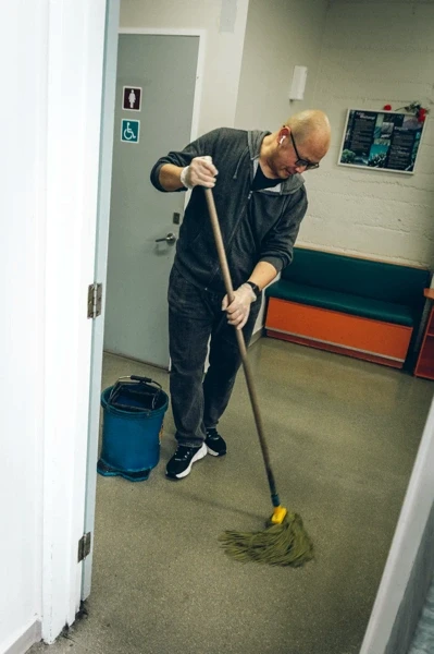 Volunteer mopping the floor inside a community support space