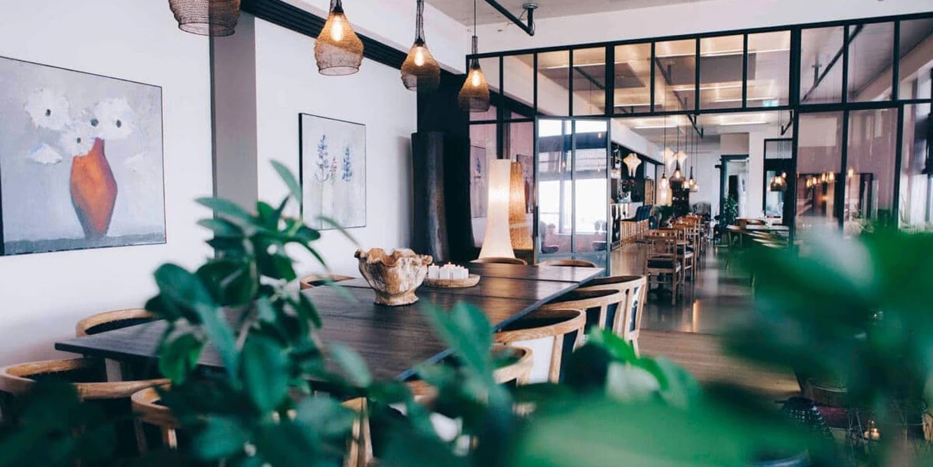 Modern hotel restaurant interior with wooden tables, hanging pendant lights, and a bright open layout
