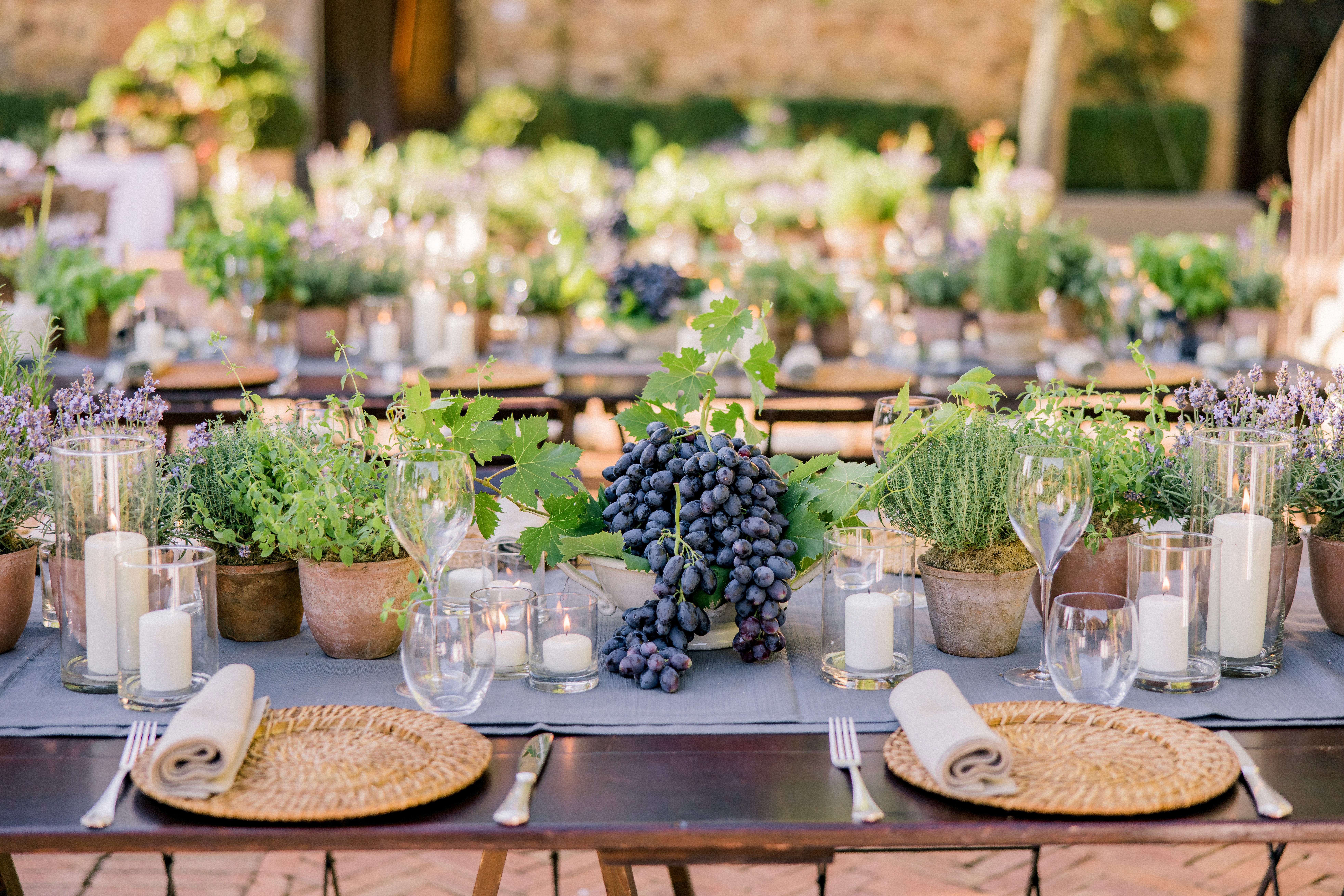 Tavola elegante per matrimonio ed evento aziendale con servizio di luxury catering, decorazioni naturali, uva, candele e mise en place raffinata all’aperto