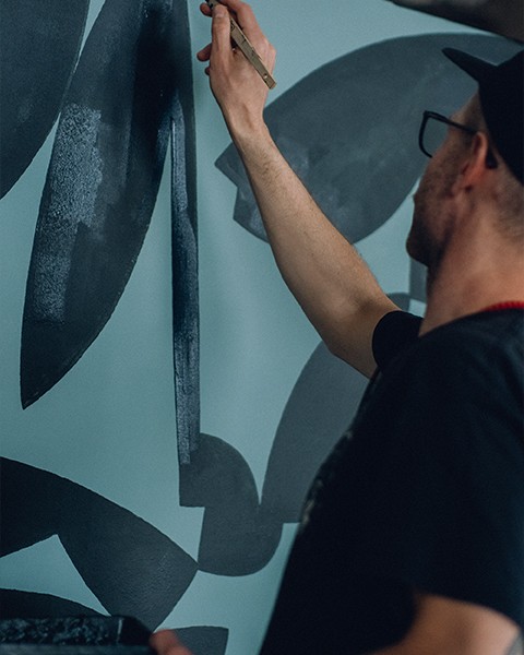 Zdjęcie przedstawiające artystę, który maluje obraz pędzlem.