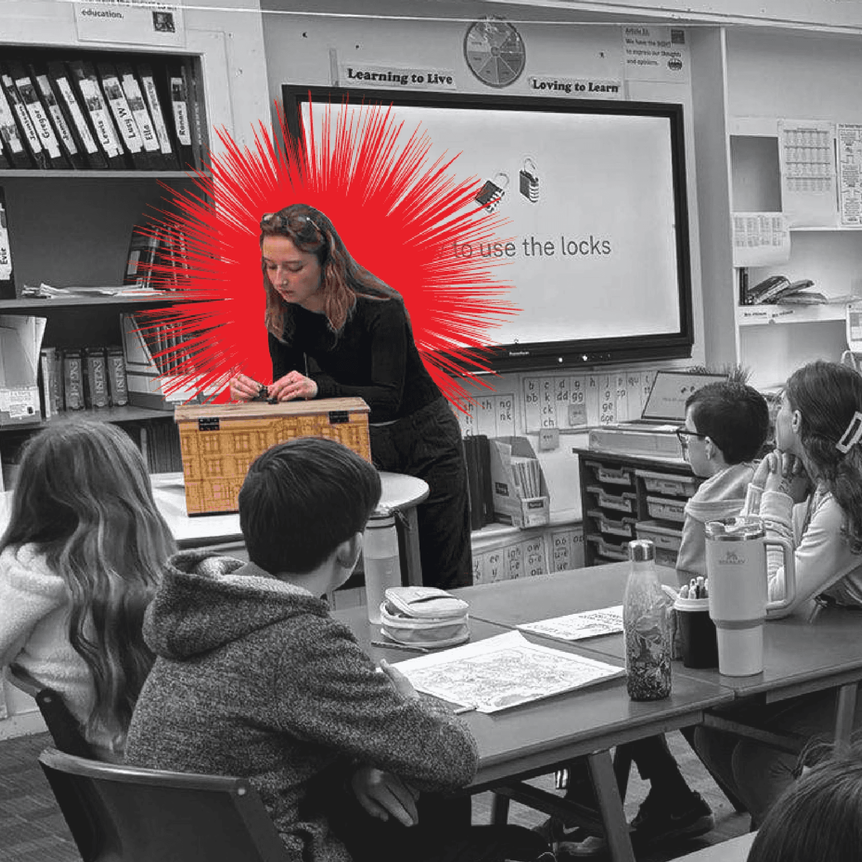 Josie at the front of a classroom demonstrating how to use a box with laser cut tenement buildings on the front.