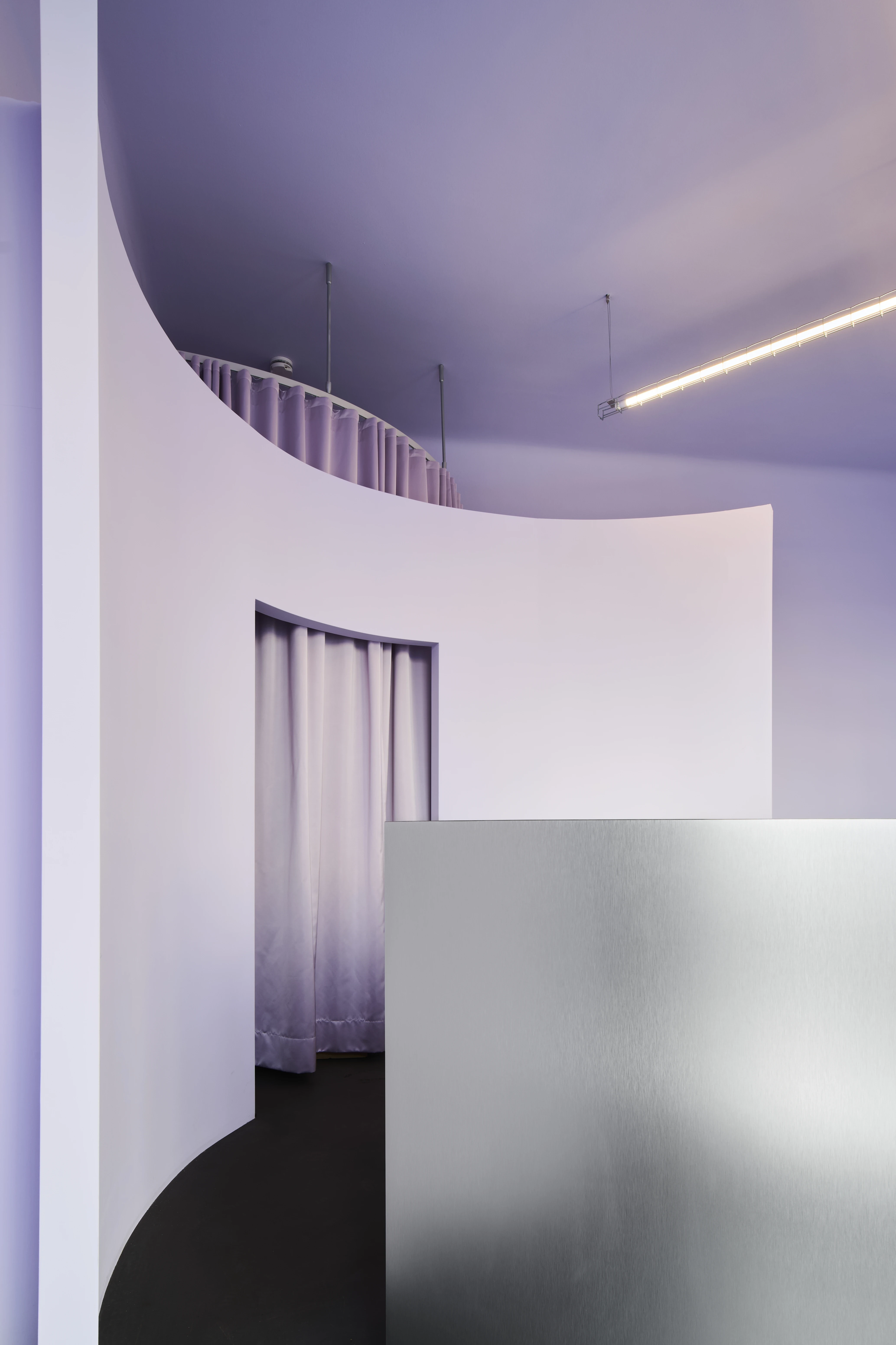 Curved lilac corridor with white walls, gradient curtain and brushed metal counter.