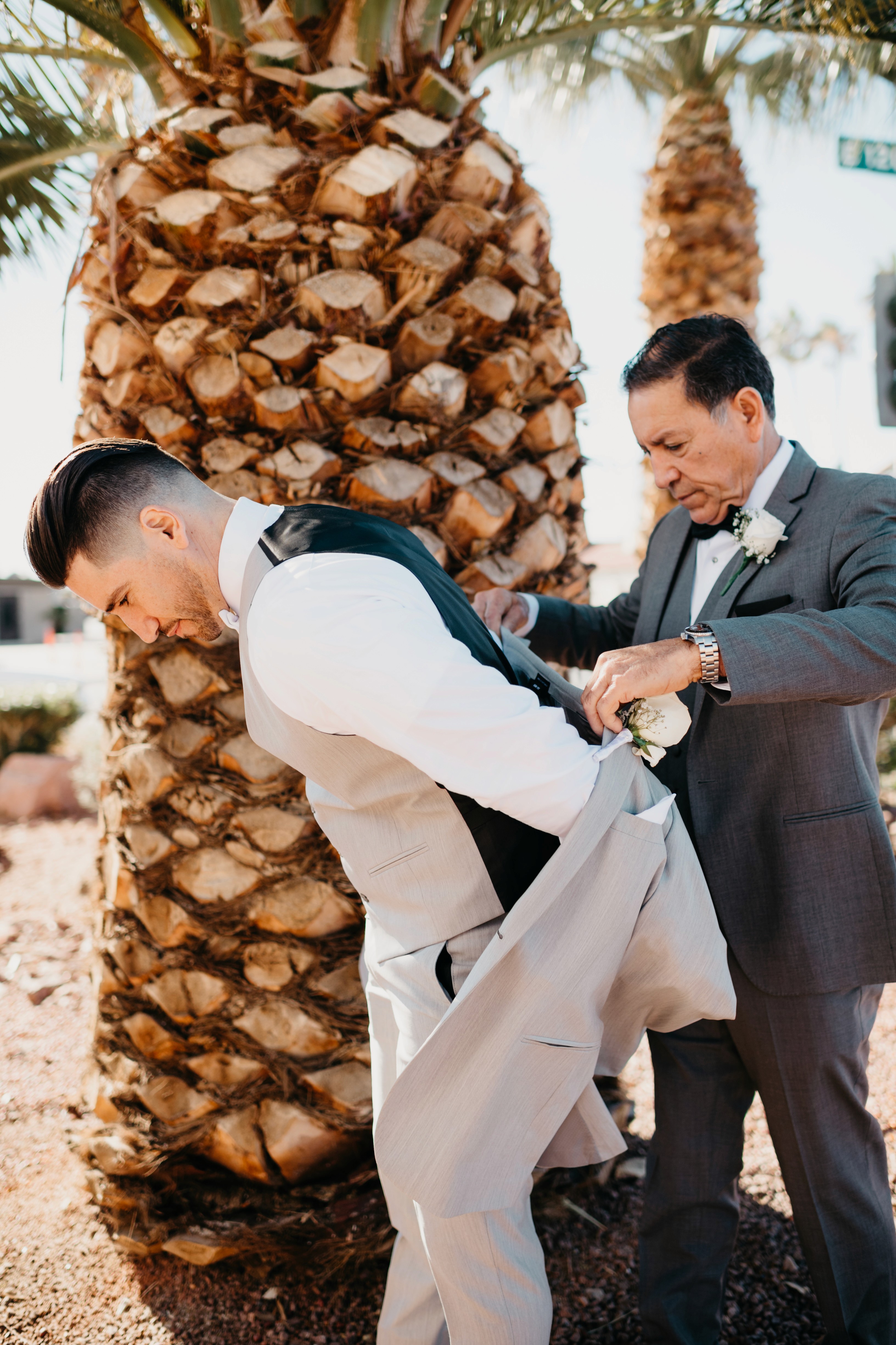 Groom getting into his wedding day suit with the help of his dad in Las Vegas