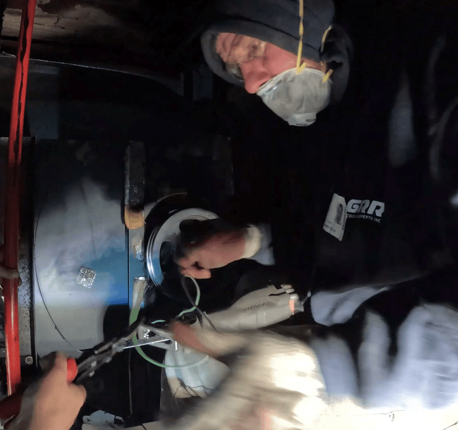 GRR Cooling Experts technician dismantling exhaust fan wiring in a tight-access mechanical room during HVAC retrofit