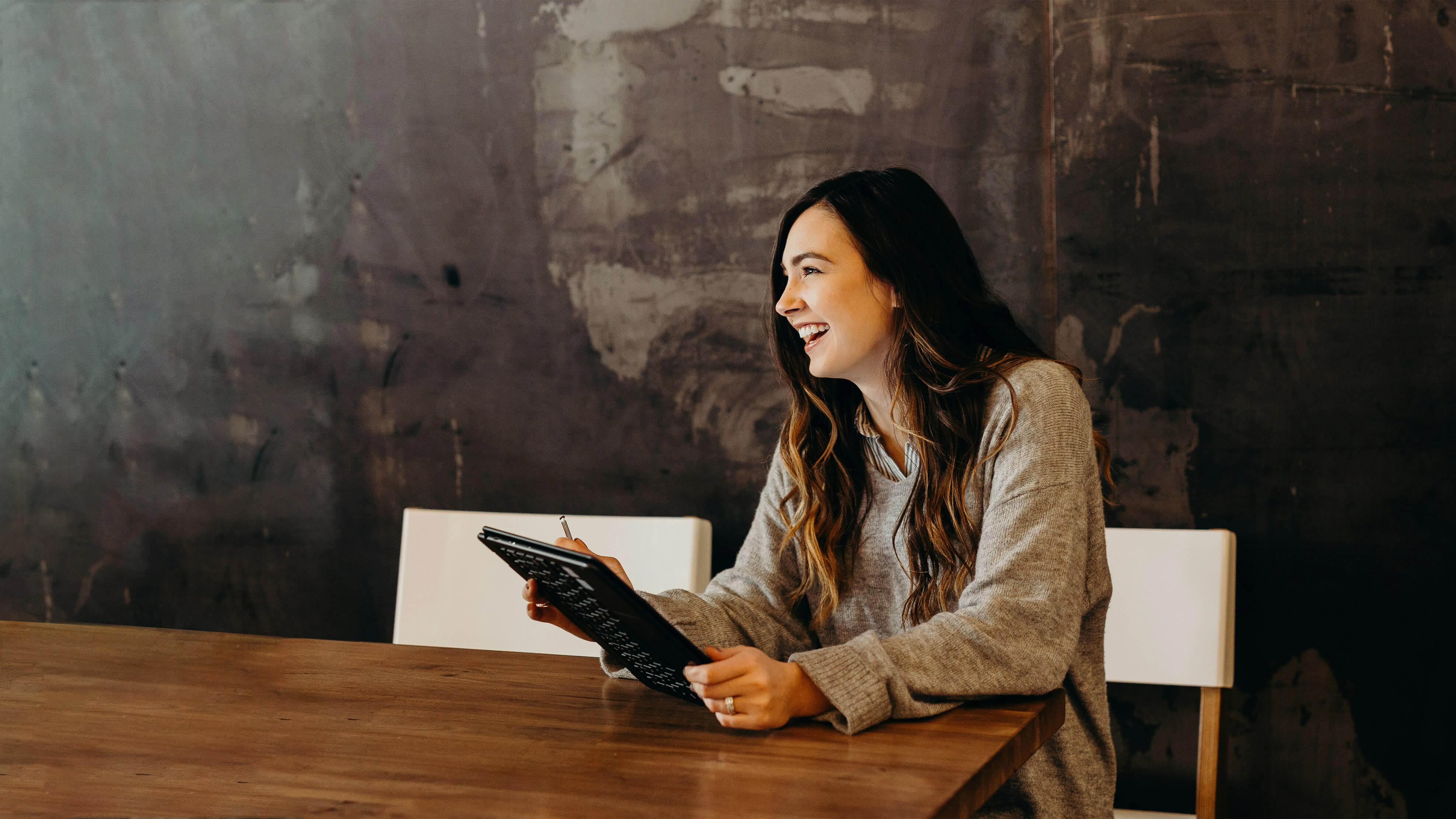 woman sitting around table holding tablet