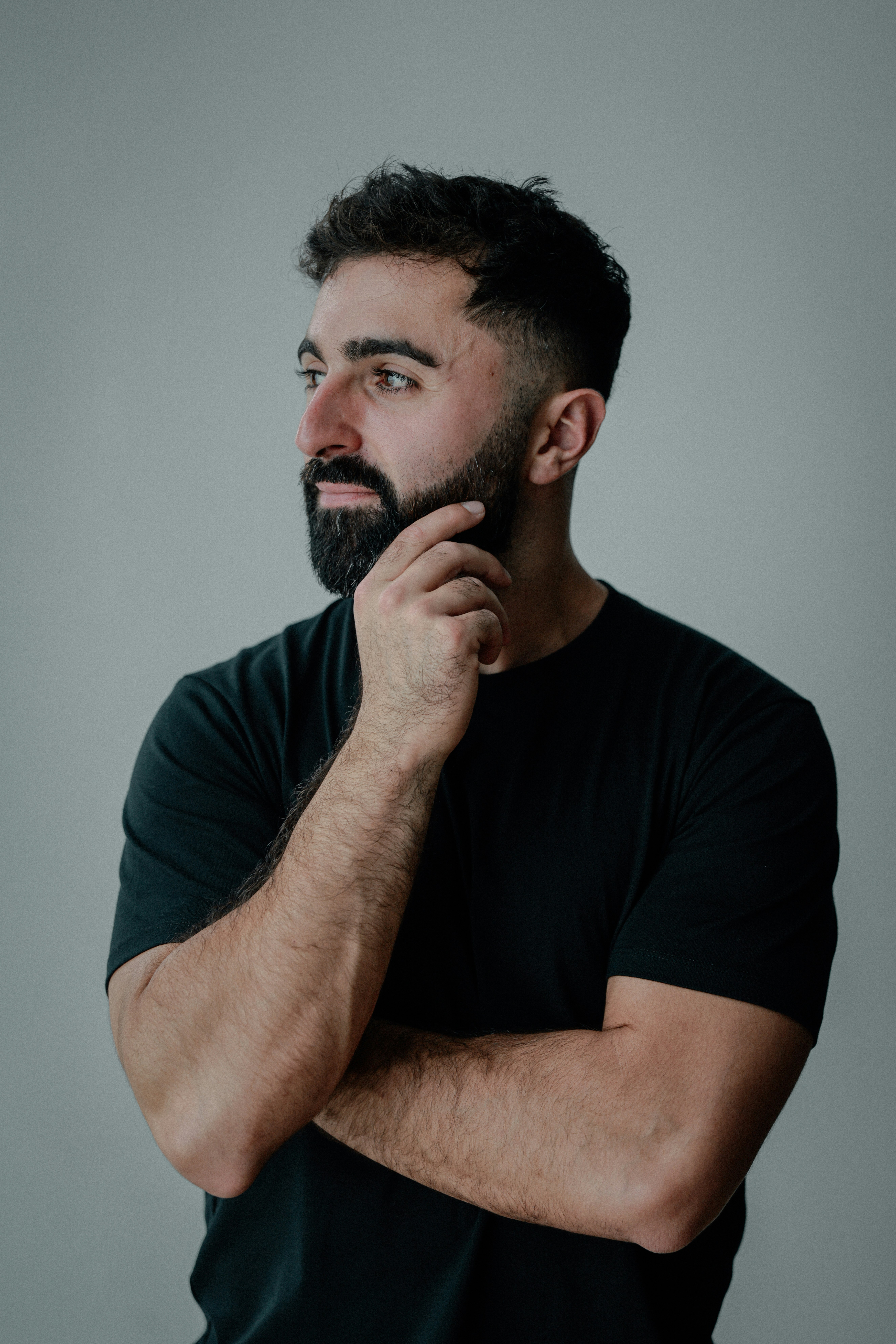 A man with a beard touches his chin thoughtfully.