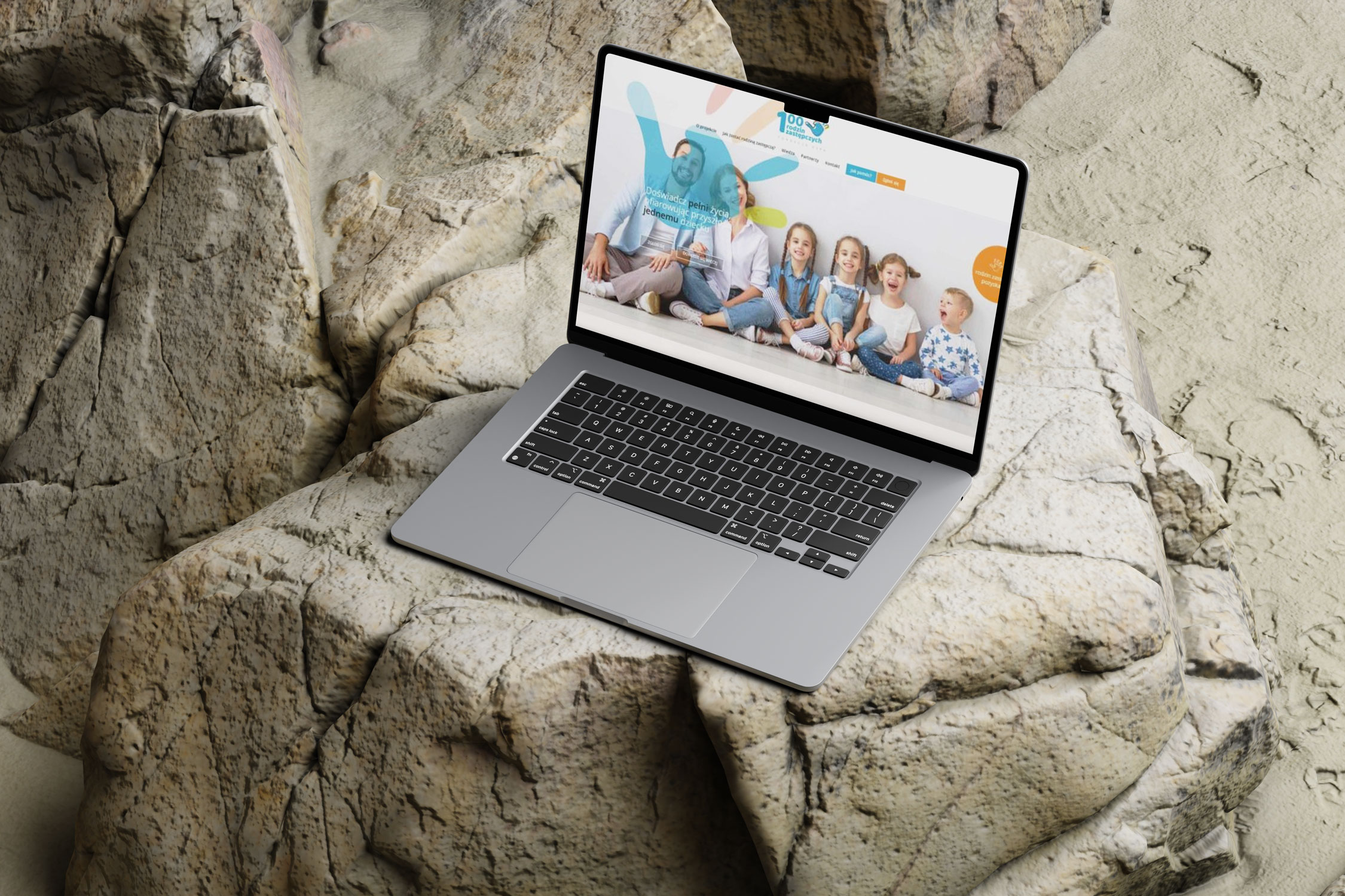 Responsywna strona główna kampanii społecznej promującej rodzicielstwo zastępcze. Mockup laptopa umieszczony w surowym skalistym otoczeniu.