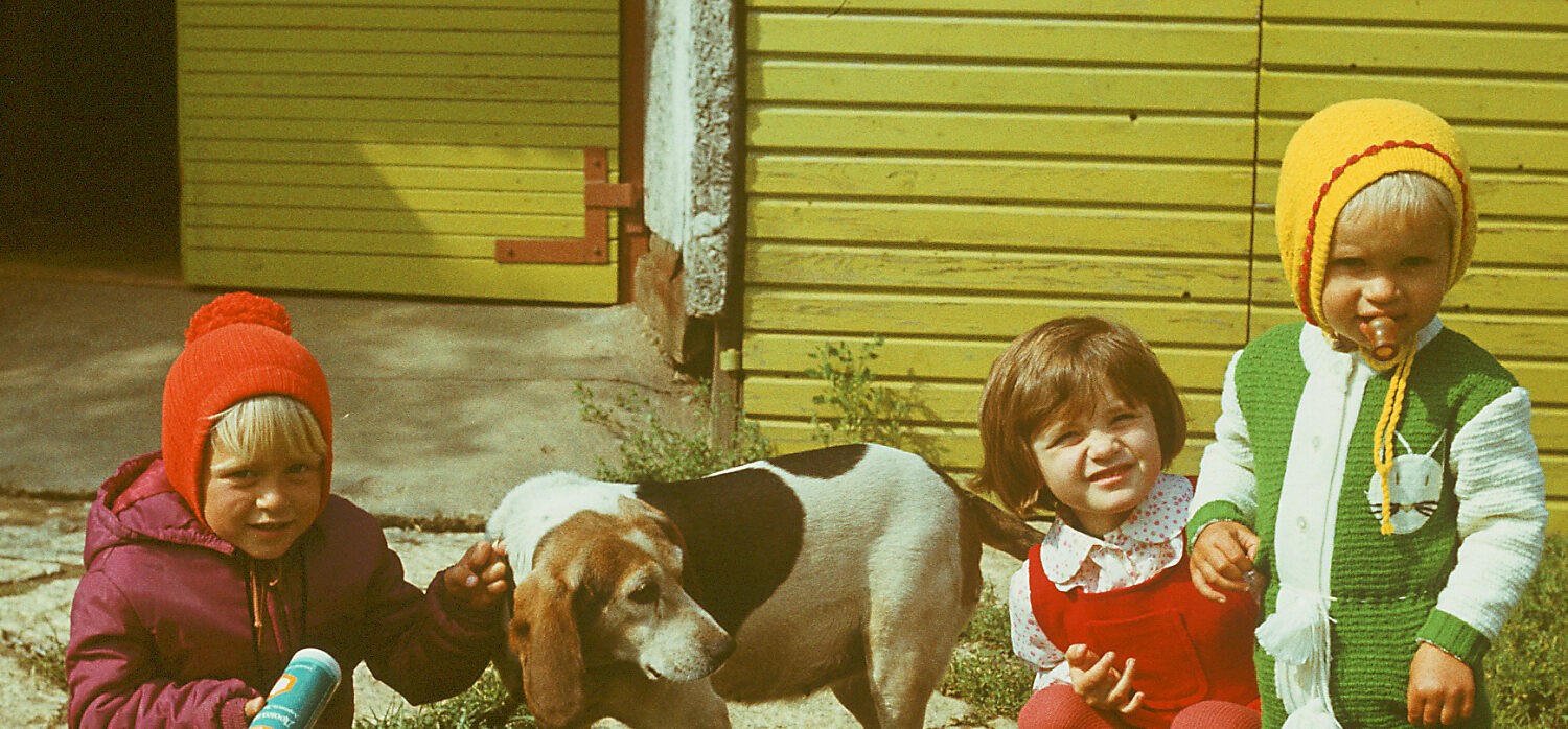 Kolm väikest last ja koer maja ees