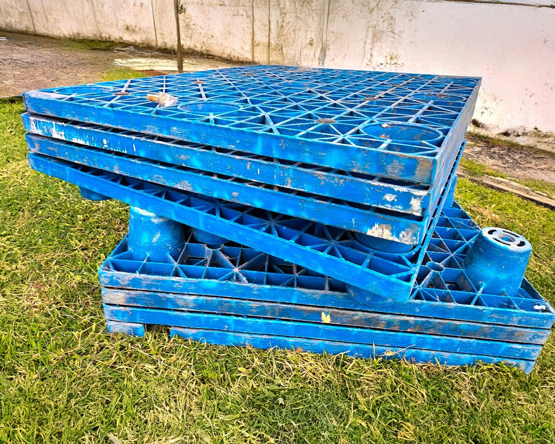 Blue plastic pallets laying in green grass