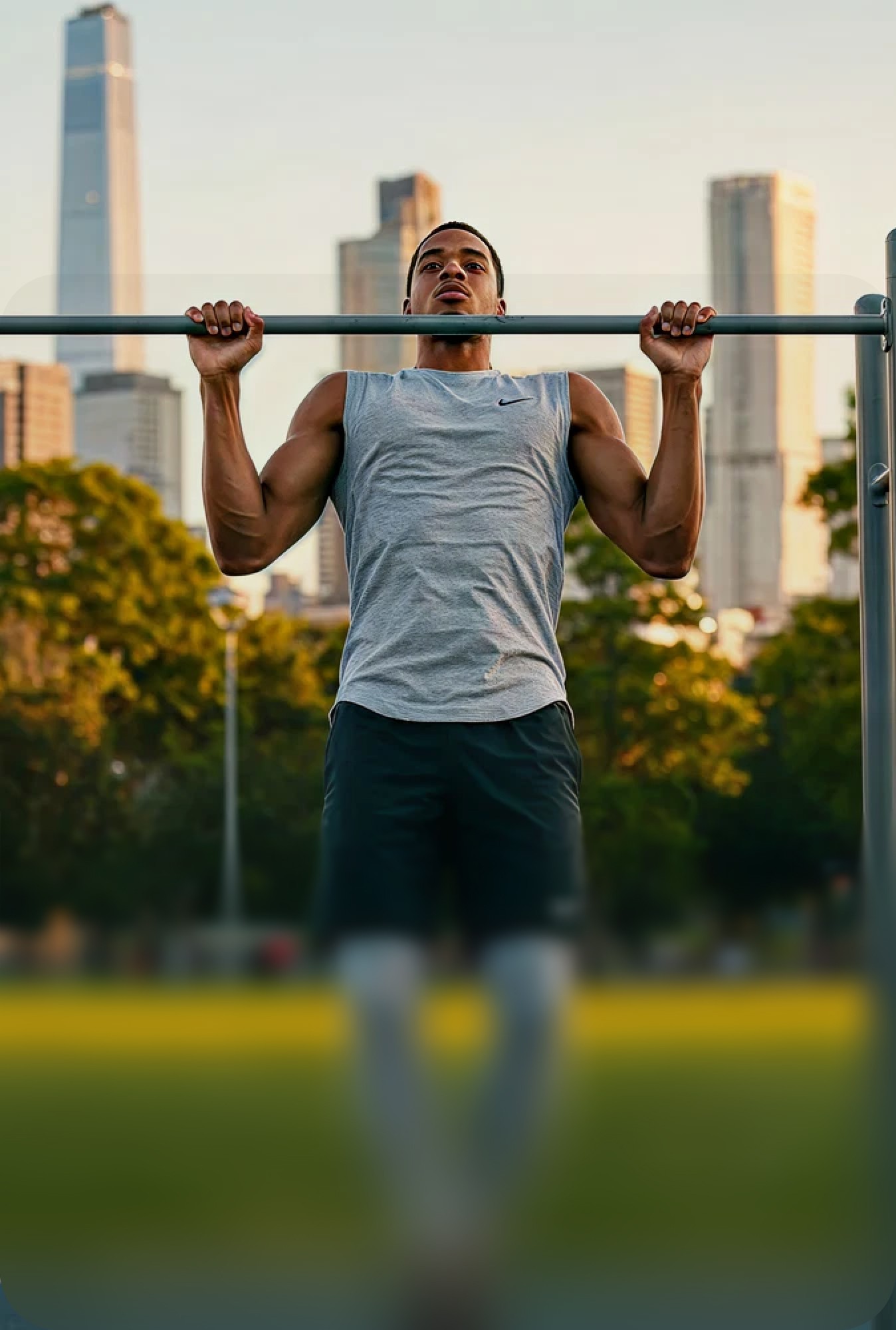A man performing an overhead stretch outdoors in a park during a workout.