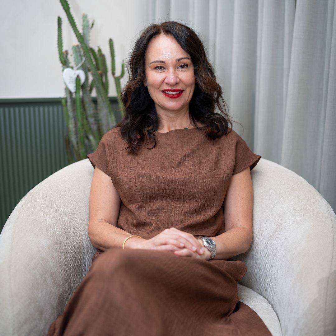 Dr. Bonnie Hawthorne sitting at a desk, smiling while using a computer, in a modern office setting.