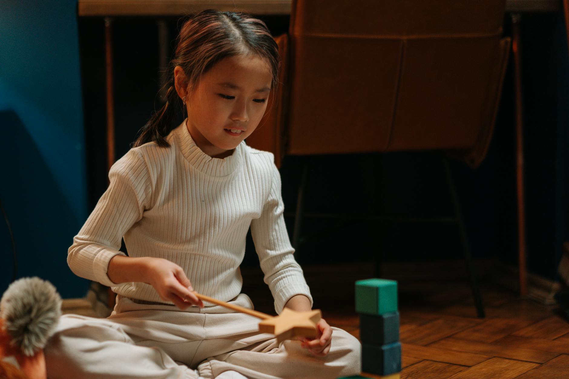 A teacher observing a quiet student who is intently building a sophisticated tower out of wooden blocks.