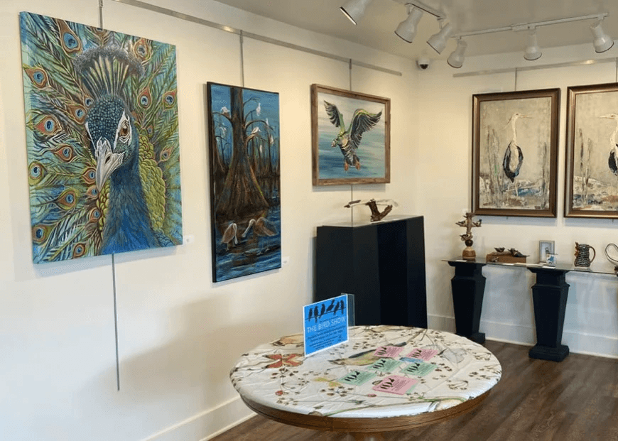 Several bird themed paintings and art pieces hung on the art gallery wall