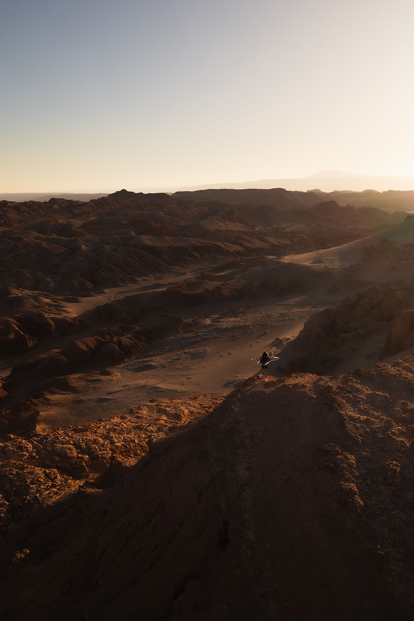 Drone view of Valle de la Luna in the Atacama Desert, Chile, with a girl holding a poncho in the wind.