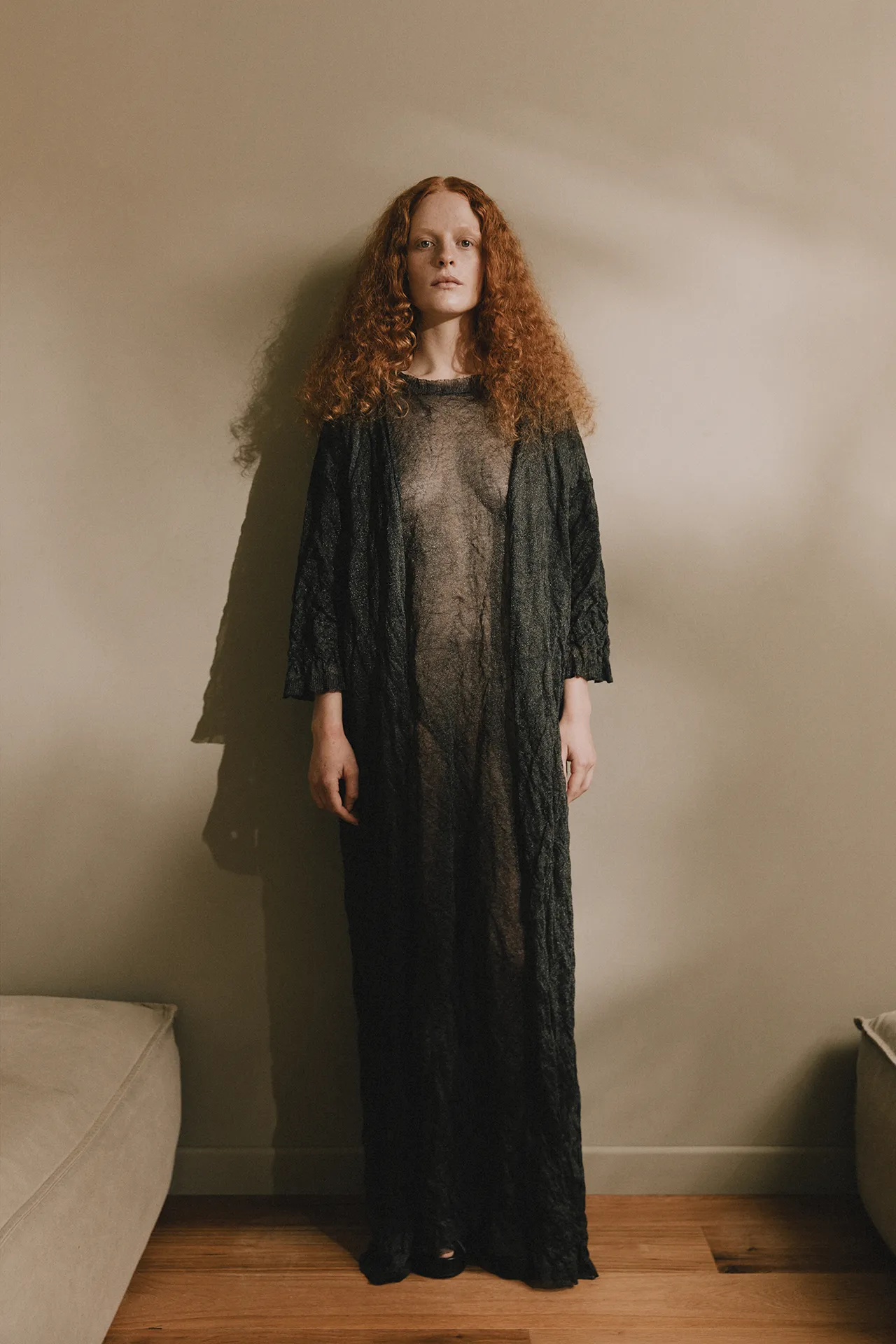 Annapurna SS26 collection sheer dark grey maxi dress with a crinkled fine-gauge knit texture and long sleeves.