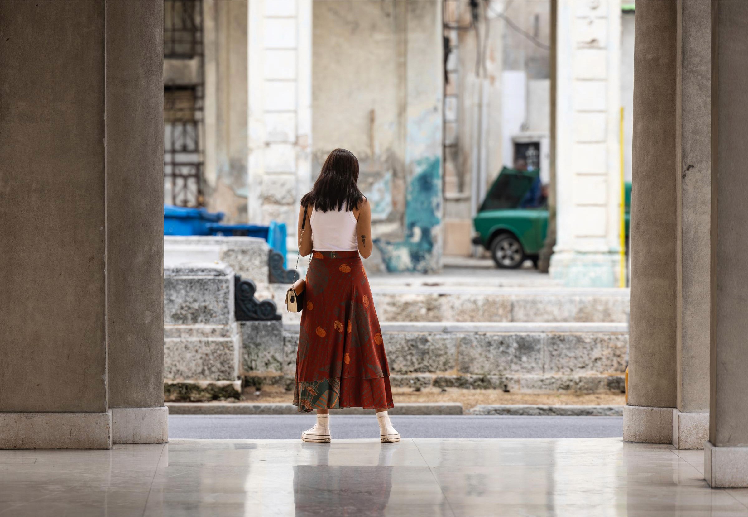 Havana, also known as the “City of Columns” or Ciudad de las Columnas because of its notable colonial architecture. A young local checks her phone between two columns.