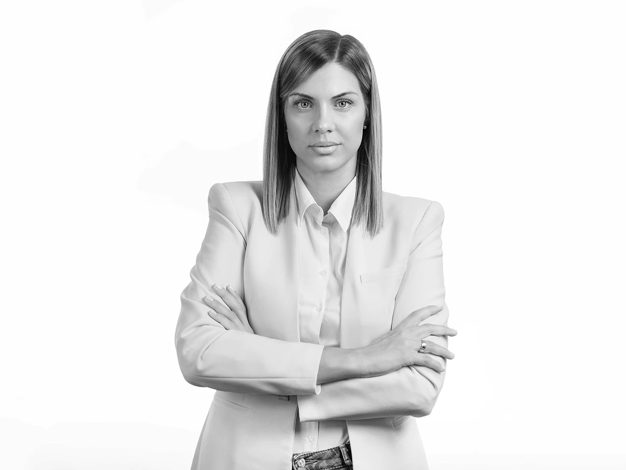 Professional businesswoman in a blazer with crossed arms against a clean studio background.