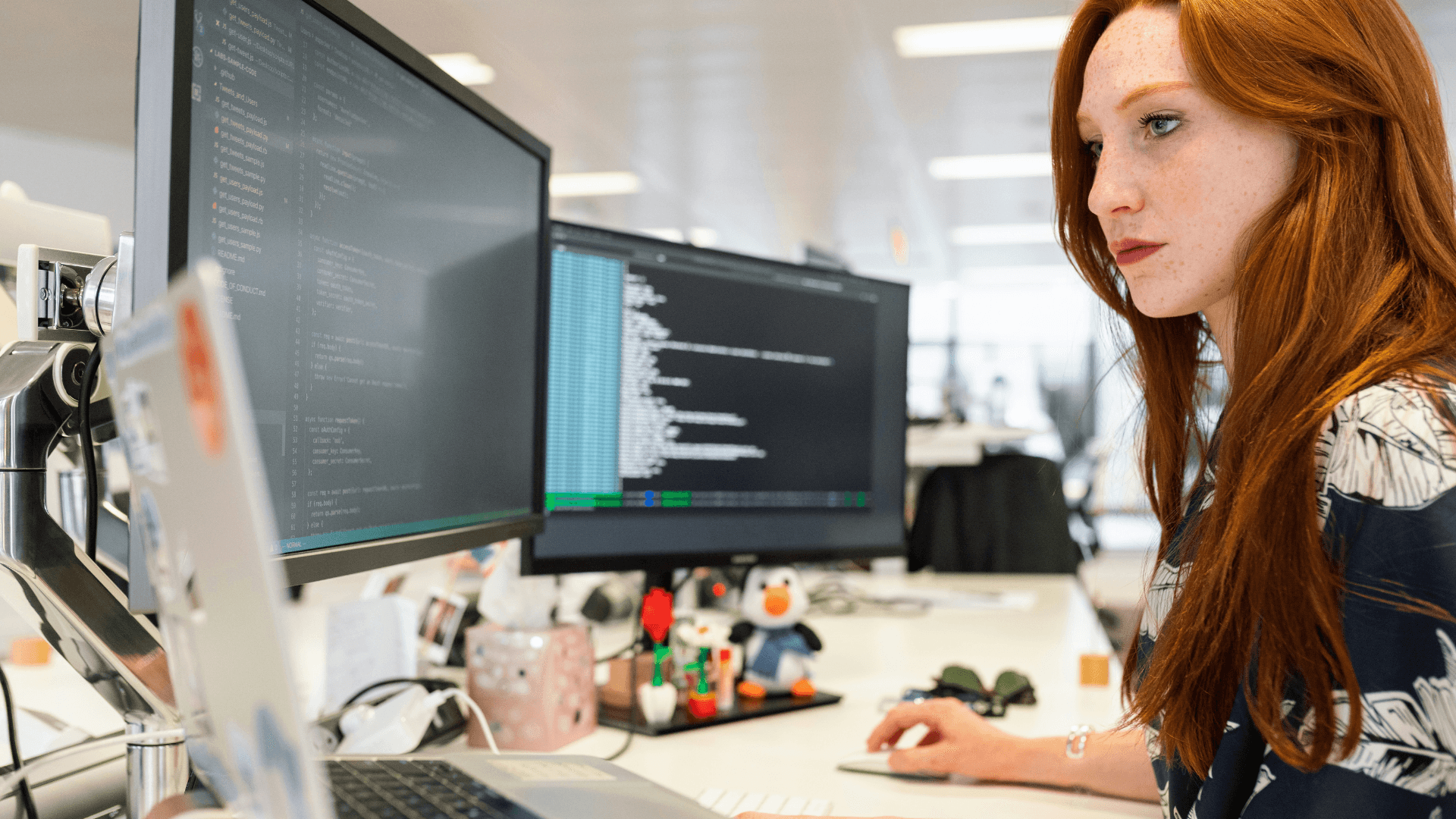A woman working at her computer with several screens filled with code