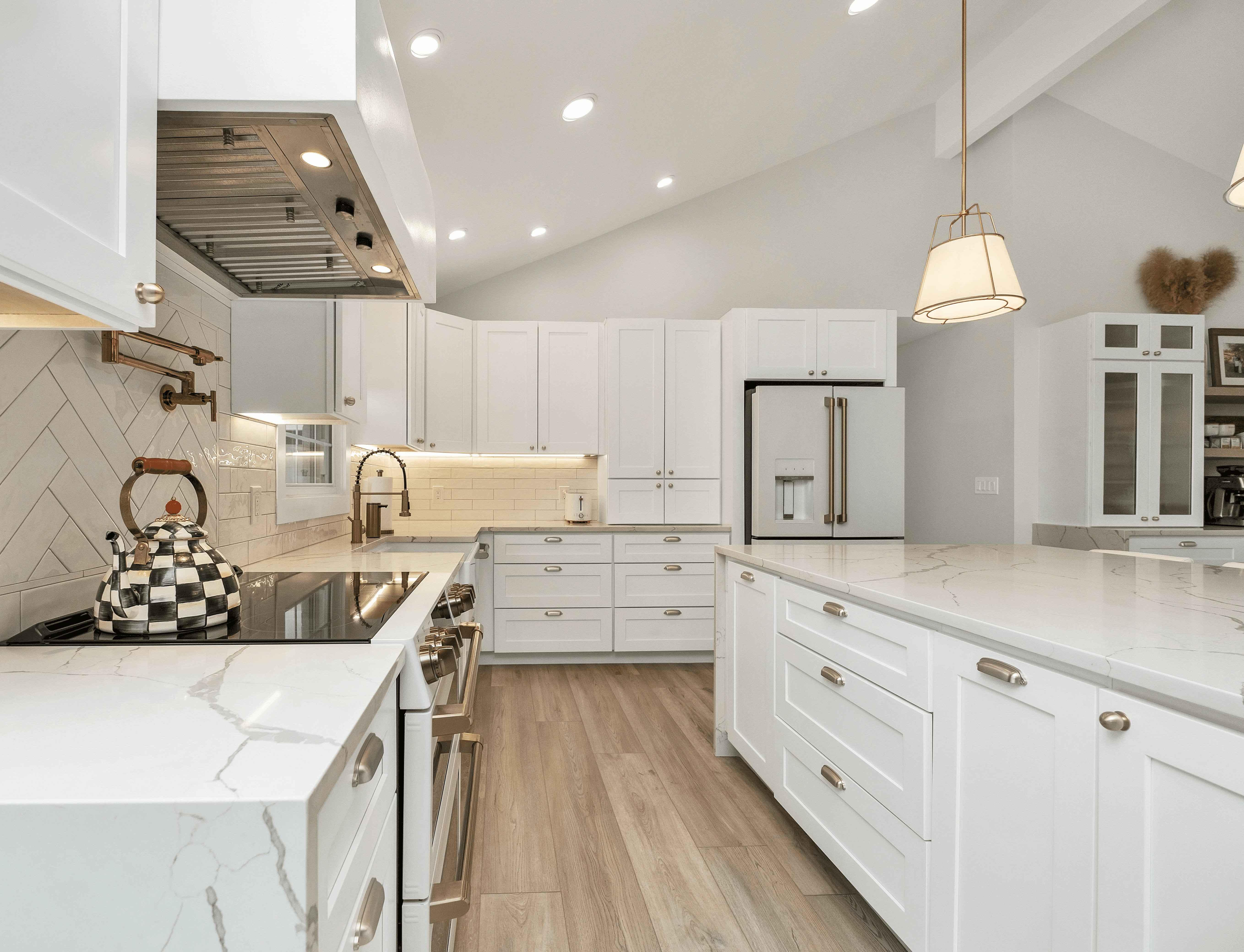 a kitchen with white cabinets and marble counter tops