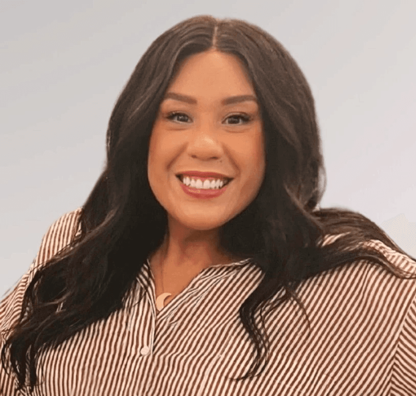 Tiffany, a light skinned Latine with long dark brown hair weaing a striped shirt and smiling warmly at the camera.