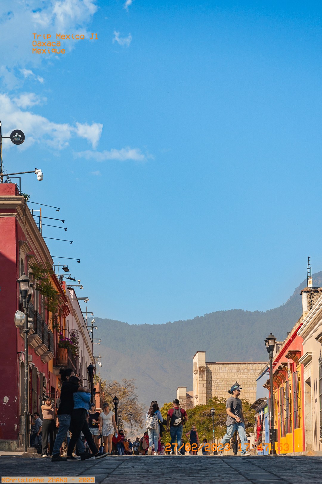 Promeneurs sur rue pavée bordée de maisons colorées à Oaxaca.