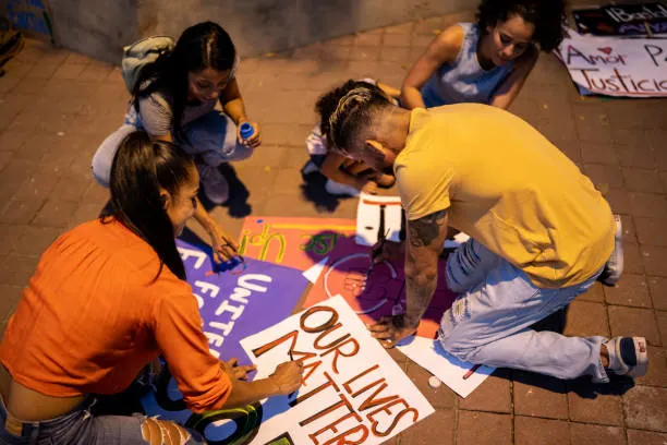 High school students and young activists preparing protest signs for social change, highlighting themes of civic engagement in RISE Research summer programs.