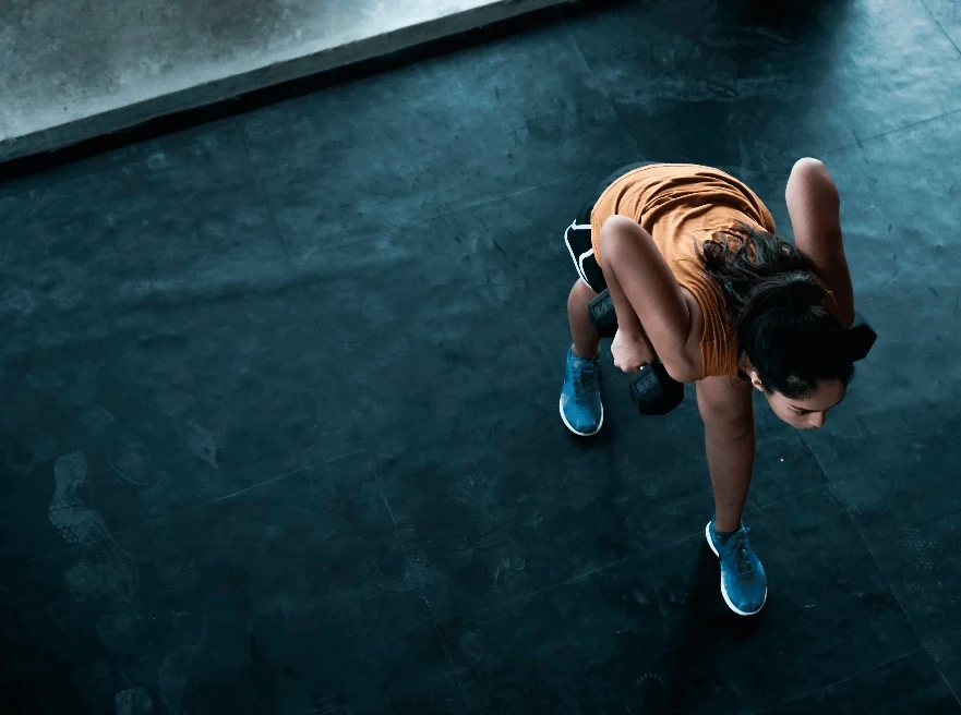 A dog with blue booties is seen running on a dark surface, captured from an overhead perspective.