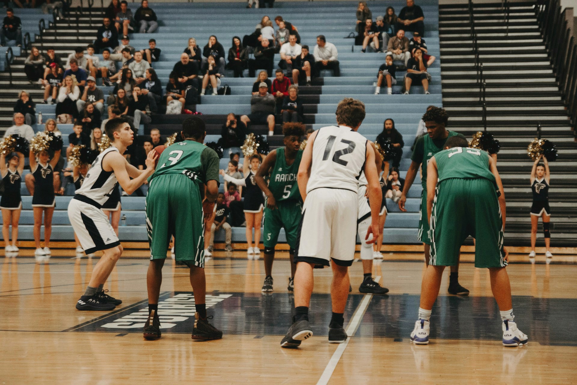 A basketball player in white guards an opponent in green holding the ball during a game.
