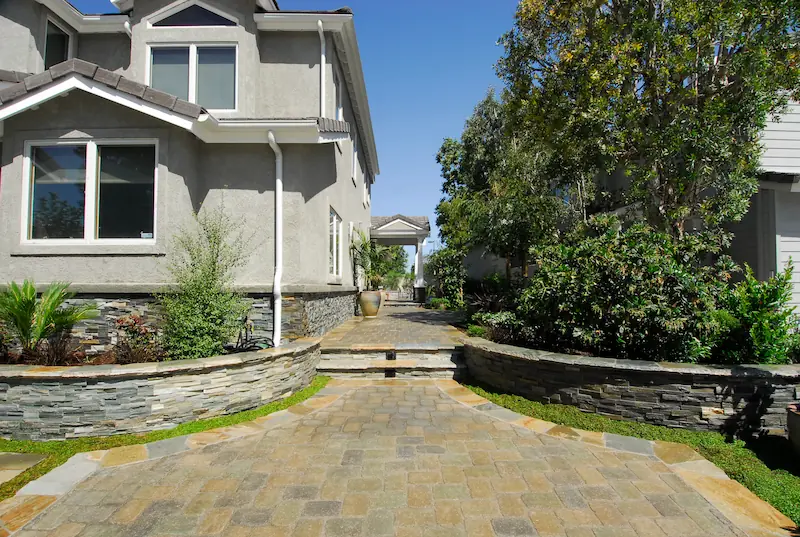 Stone pathway leading to arched entry, flanked by lush planters at Irvine Transitional Modern. Photo by Chris Darnall.