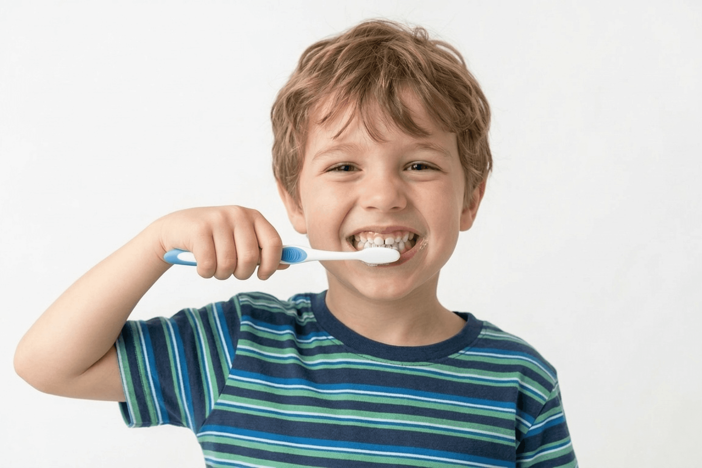A young child holding a toothbrush and smiling, emphasizing the importance of early preventive dental habits.