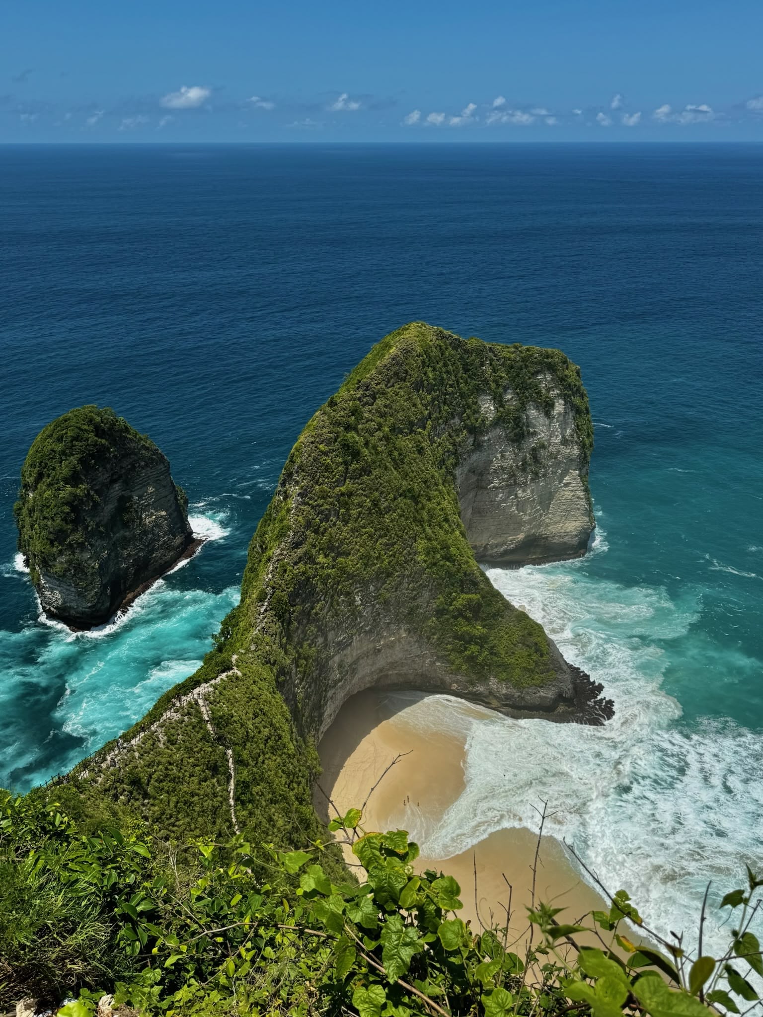 A smiling young man with crossed arms, wearing a plaid shirt and white t-shirt, poses against a dark background.