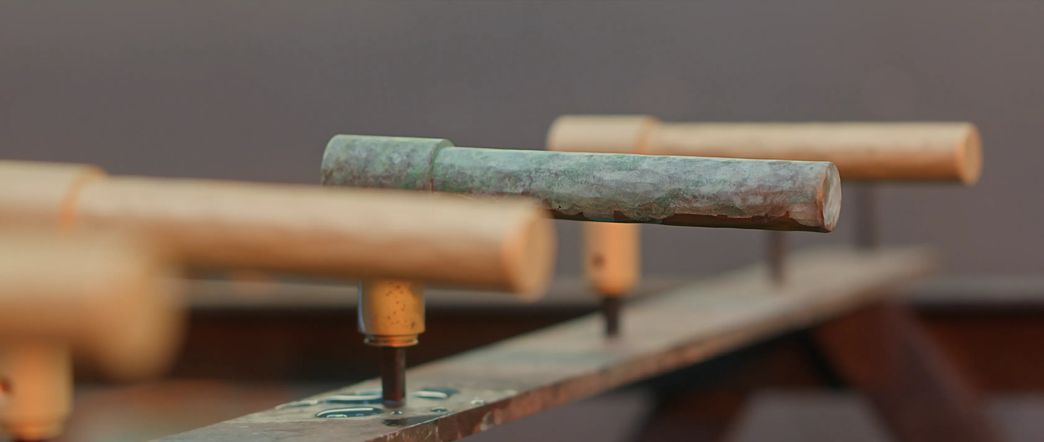 Close-up of a well-worn foosball handle, showing textured wood with a hint of aging, set against a blurred background, highlighting its vintage appeal.