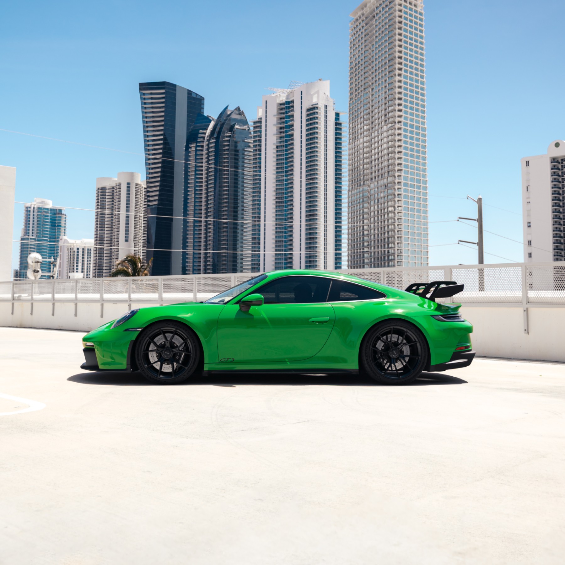 Side profile of a green Porsche 911 GT3, emphasizing its aerodynamic lines and sport-tuned stance.
