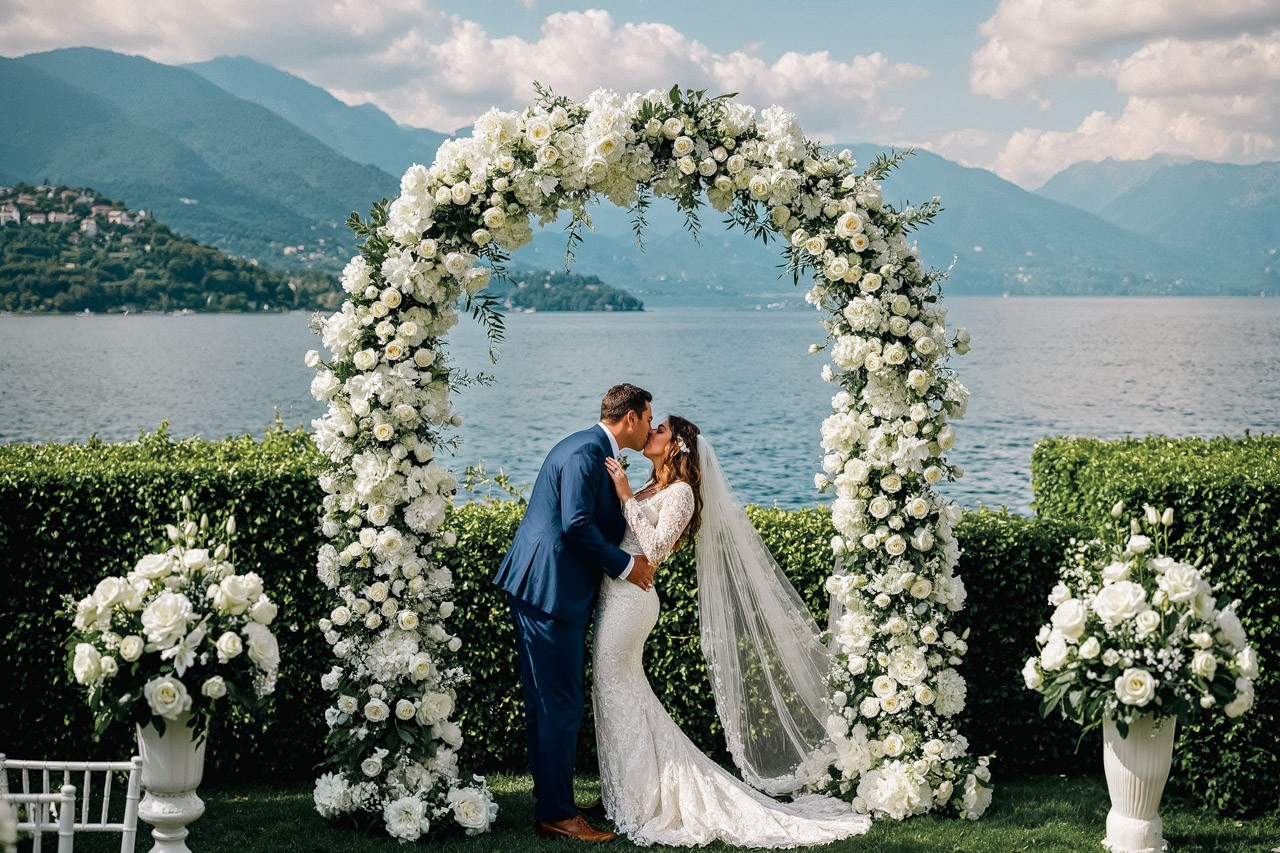 a wedding couple under a arch in the front of the lake