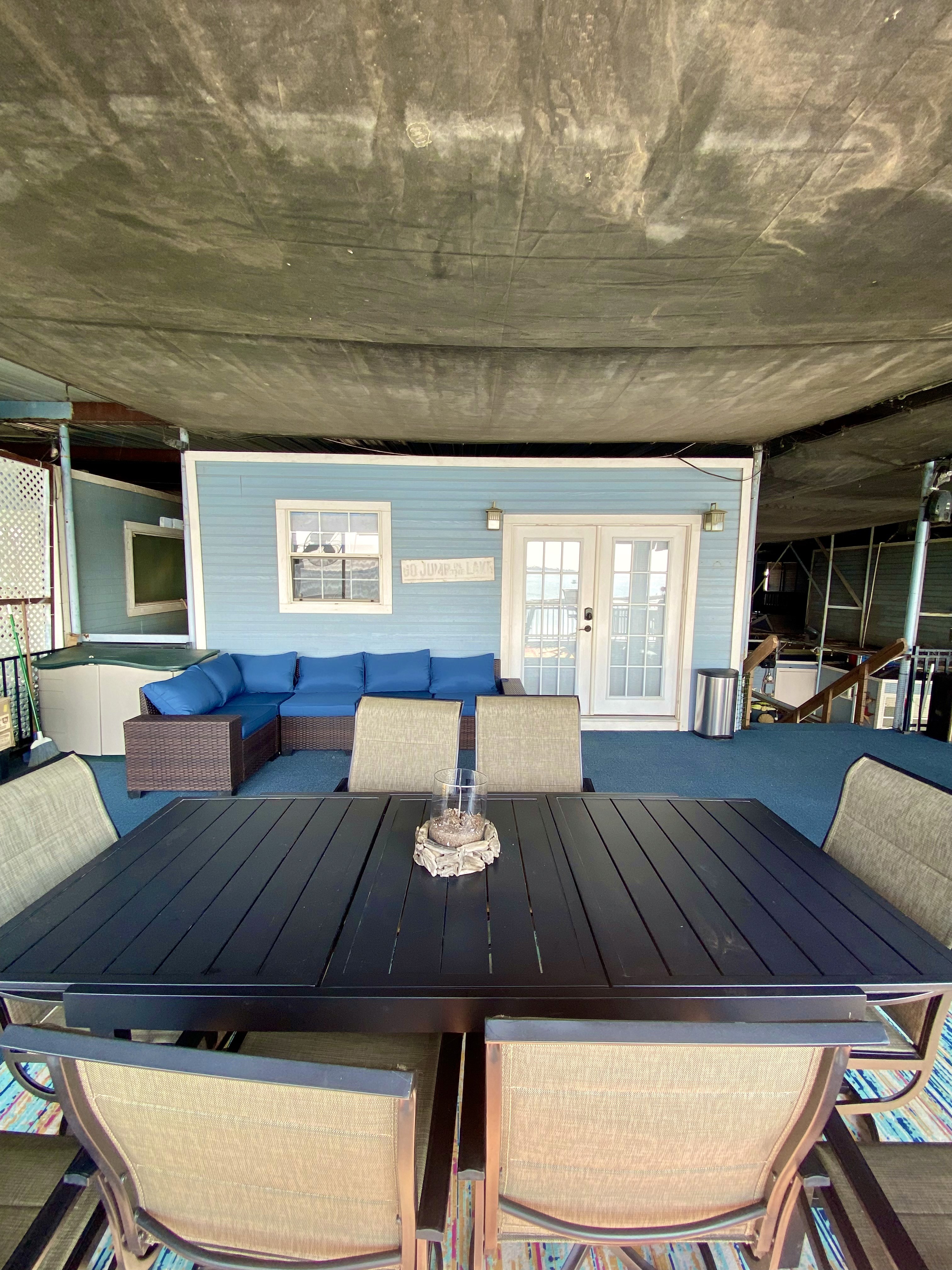 Outdoor patio with a dining table and chairs, and a blue sectional sofa near French doors.
