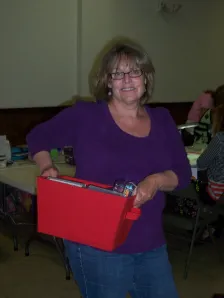 Woman carrying a red supply tote at a crop