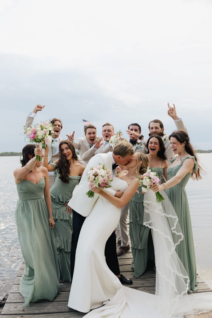     Wedding photographer South Florida captures a joyful bridal party celebrating by the water after the ceremony.