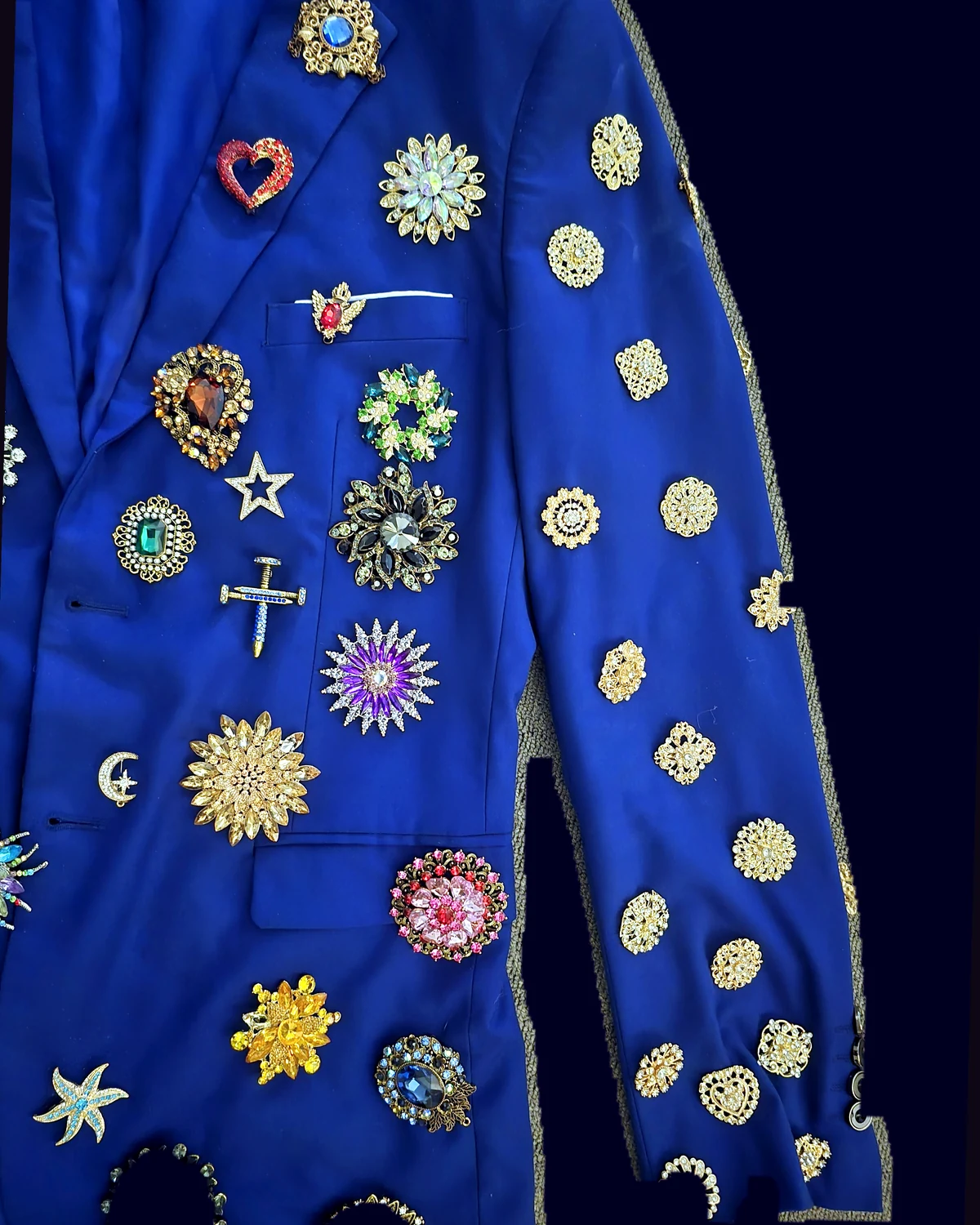 Right side detail of the Wonder Suit jacket with its original brooches under a saturated chrome color grade.
