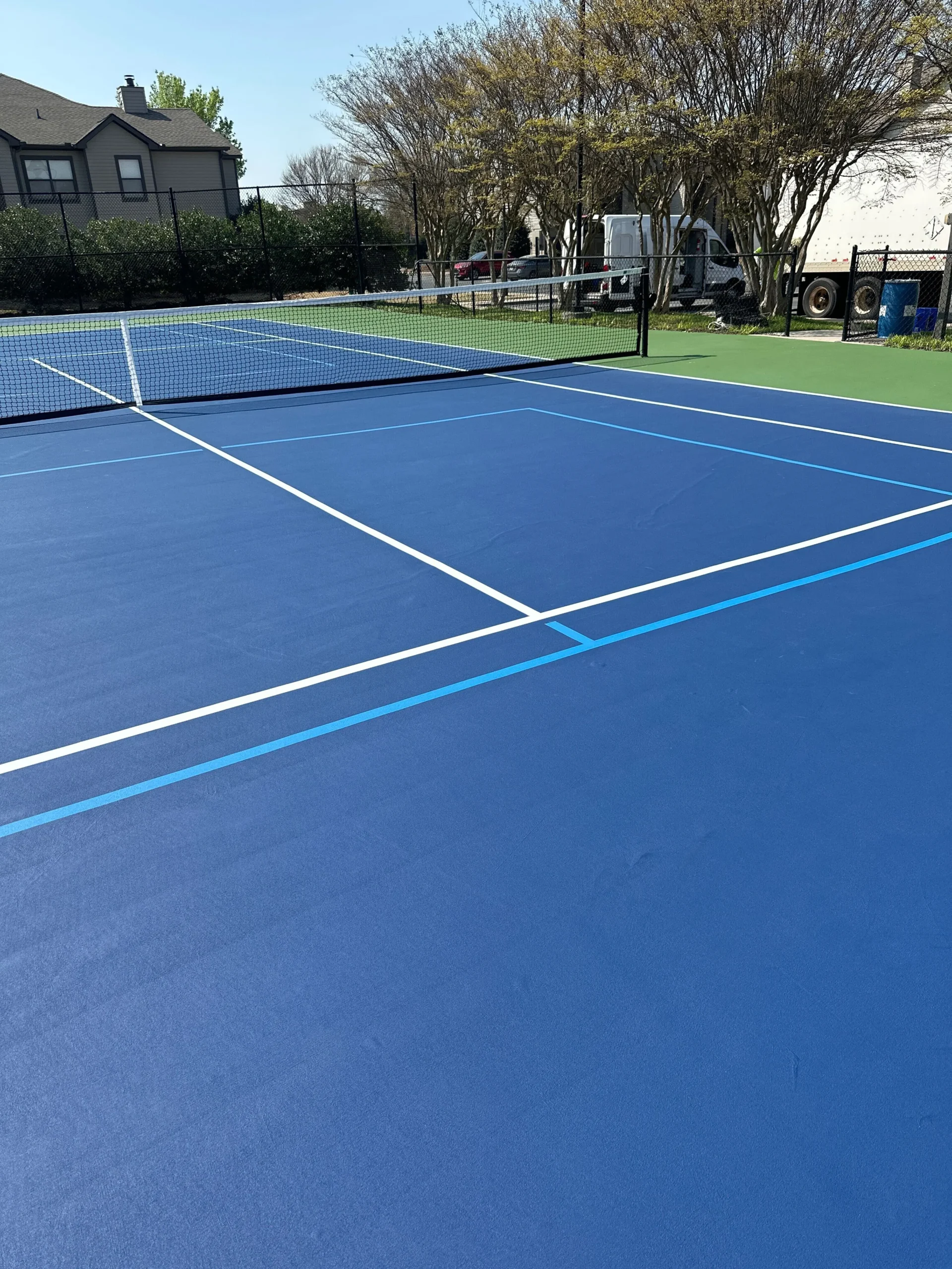 Resurfaced tennis court with crisp white and blue line striping at Weston Ranch in Madison, AL