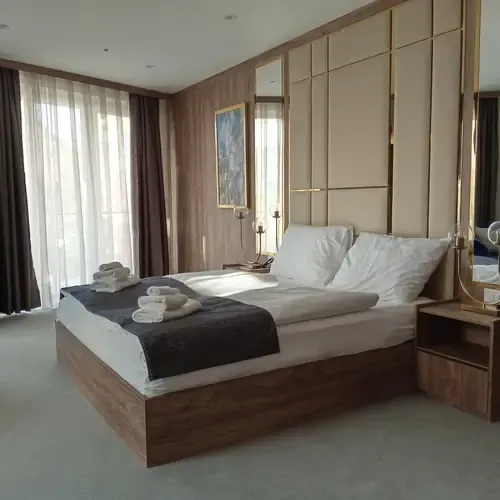 Woman sitting in sunlight with eyes closed, wearing relaxed neutral clothing in a peaceful setting.