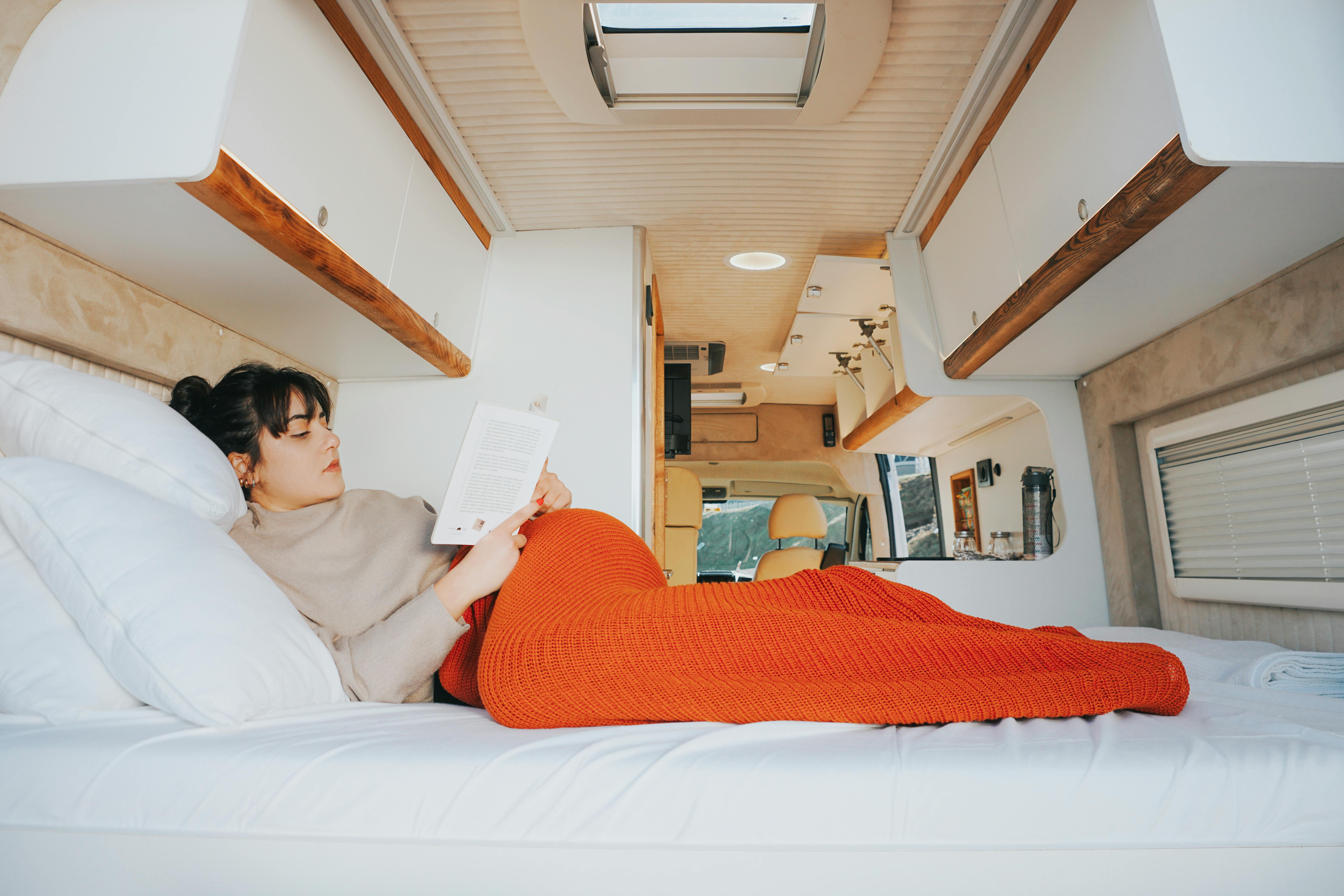 Une femme lit un livre sur les assurances dans son camping car