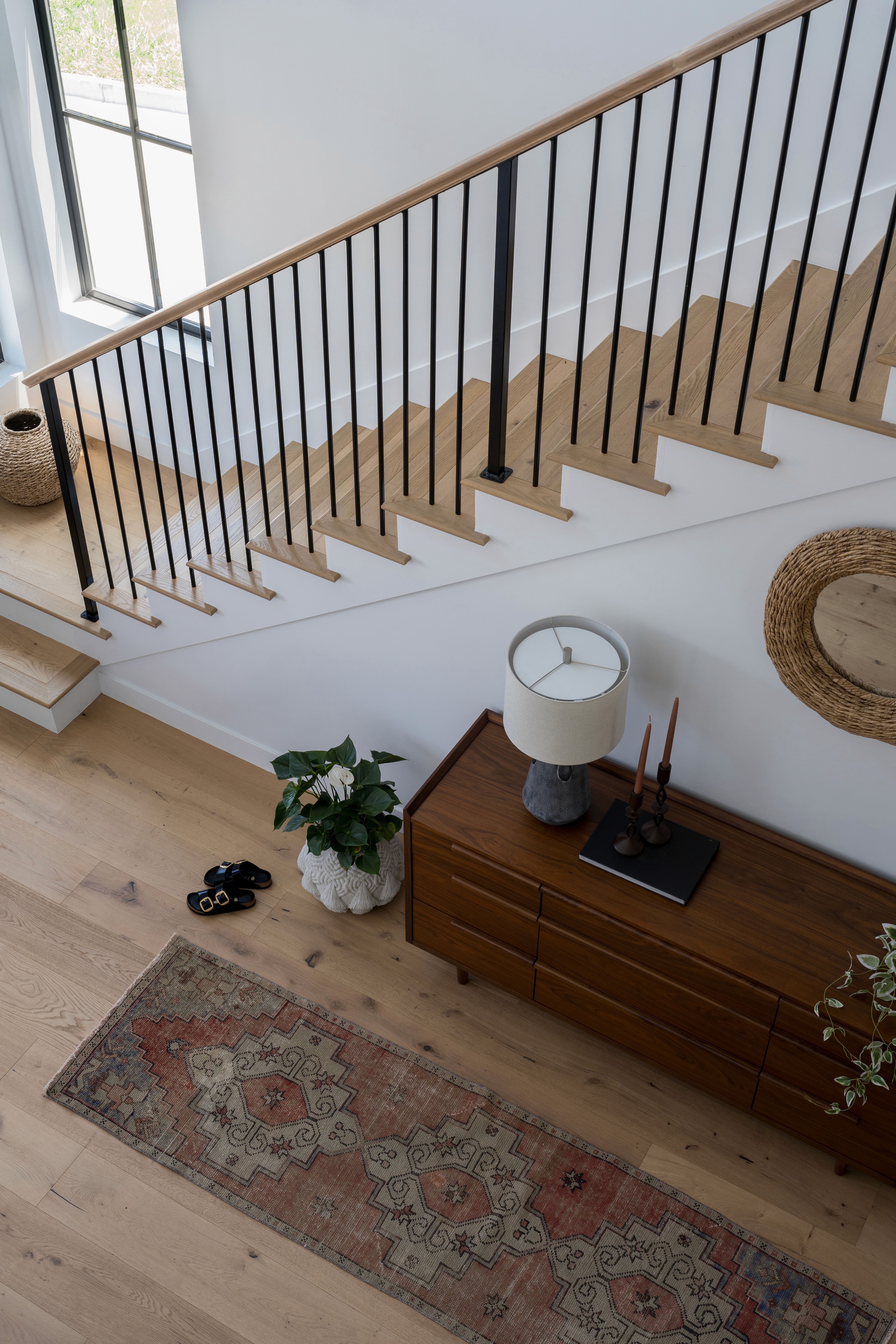A welcoming entrance with a minimalist console table, decorative mirror, and soft lighting. The space is accented with a textured rug and hints of greenery, giving a fresh, inviting feel by Jubilee Interiors in Lakewood, California
