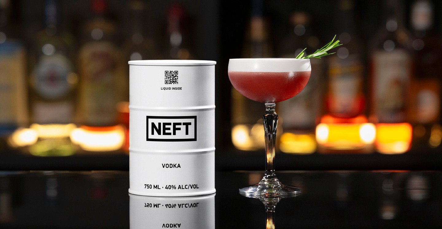 A NEFT Barrel and a glass of Pomegranate Cape Cod on a bar counter.