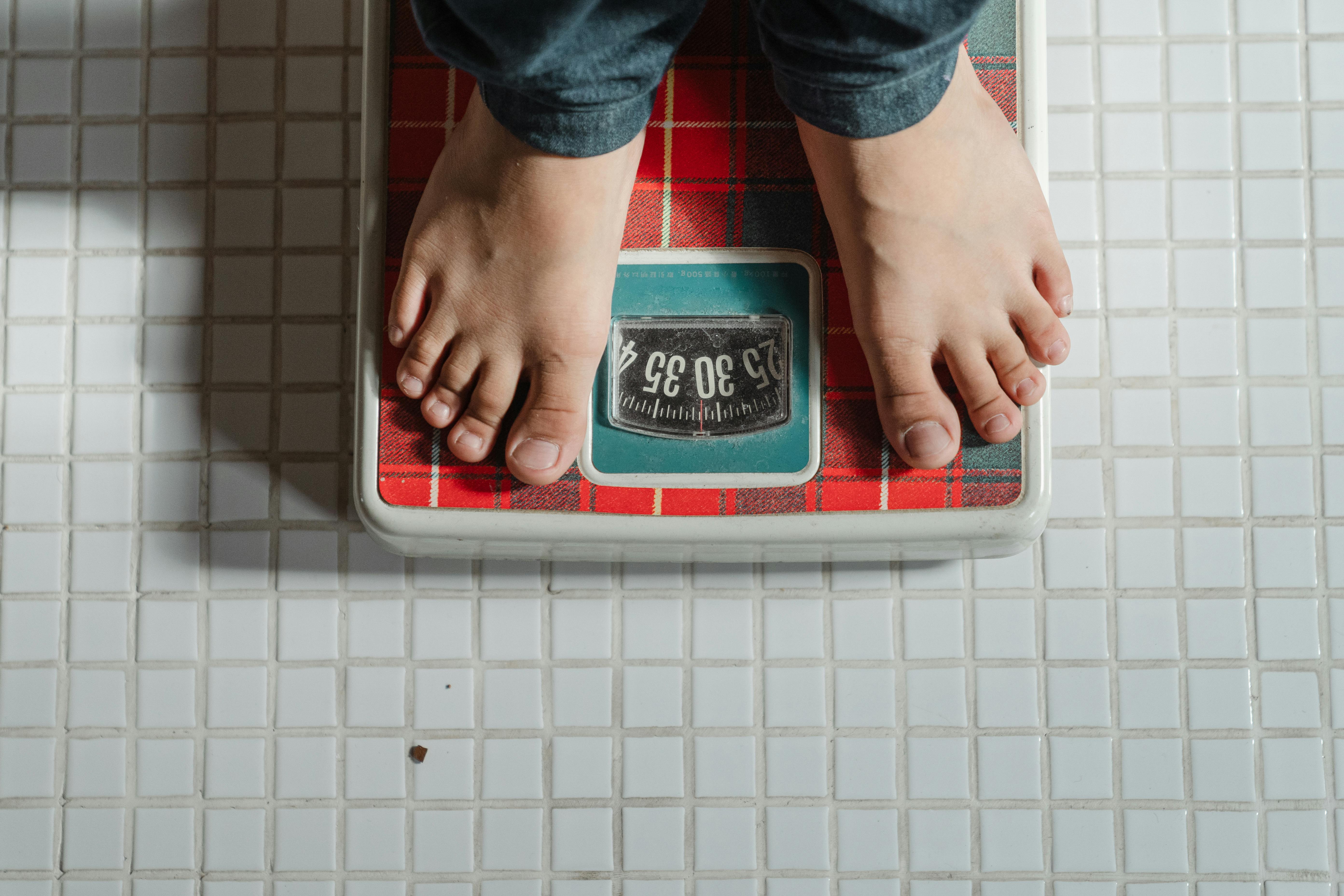 from-above-crop-anonymous-barefoot-child-in-jeans-standing-on-weigh-scales-on-ti - ketut-subiyanto (pexels)