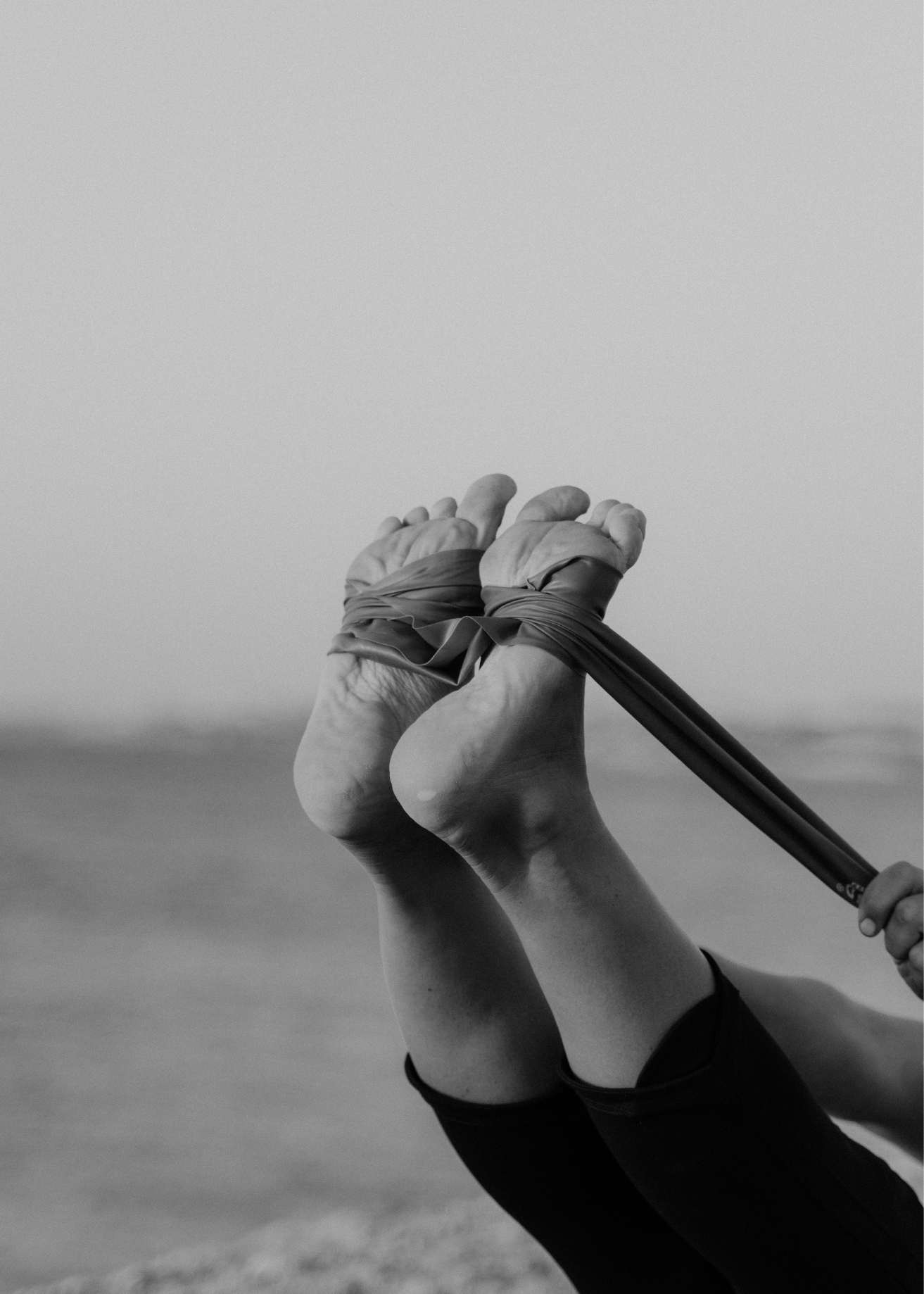 State of Soma wellness imagery showing a person’s feet in a yoga strap during mindful movement practice, used for holistic health branding.